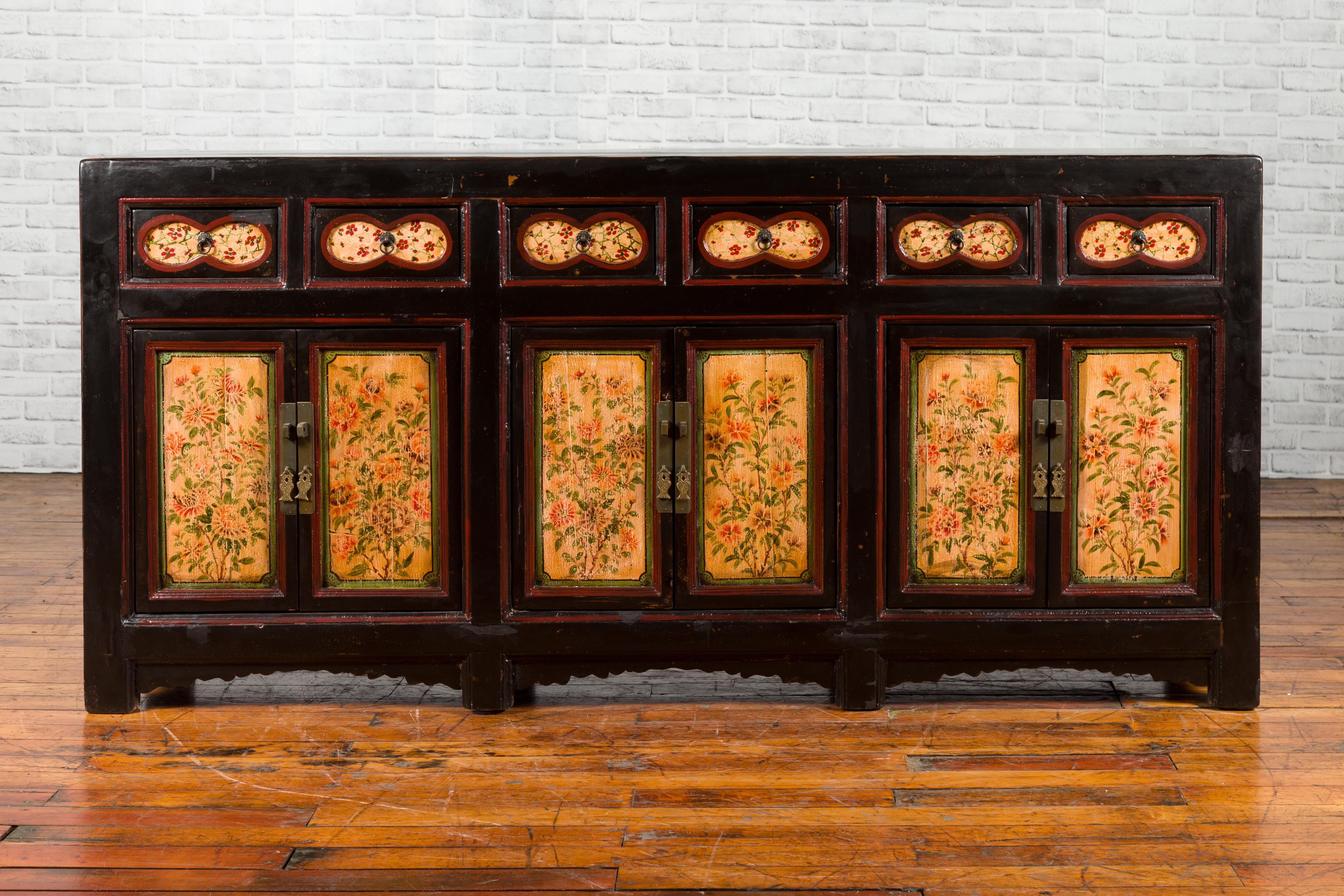 A Chinese black painted Gansu sideboard from the early 20th century, with hand painted floral motifs. Created in the North-Center province of China, called Gansu during the early years of the 20th century, this sideboard features an unusual black