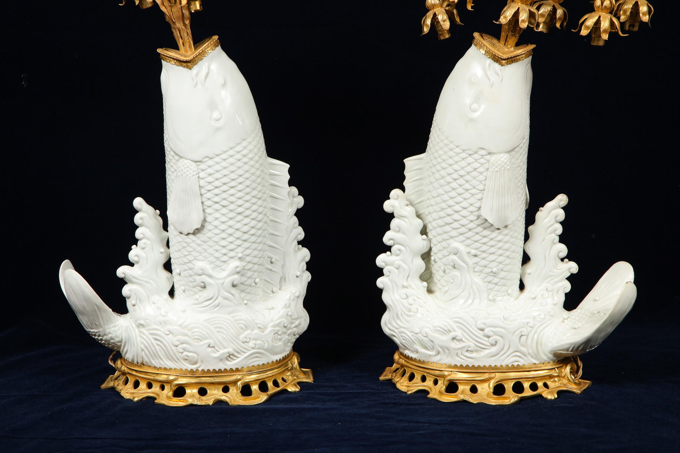 A very fine and quite unusual pair of antique Chinese fish-form Blanc de Chine porcelain vases mounted with beautiful antique French Louis XV style doré bronze fountain-form overflowing water fall eight-arm candelabra lamps. The porcelain; Chinese,