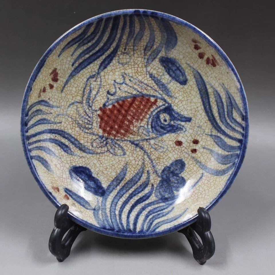 This Antique Chinese Blue and White Iron Red Fishes Plate is an exceptional piece of traditional Chinese porcelain, offering a beautiful fusion of artistry and symbolism. The plate features intricate blue and white designs, complemented by bold iron