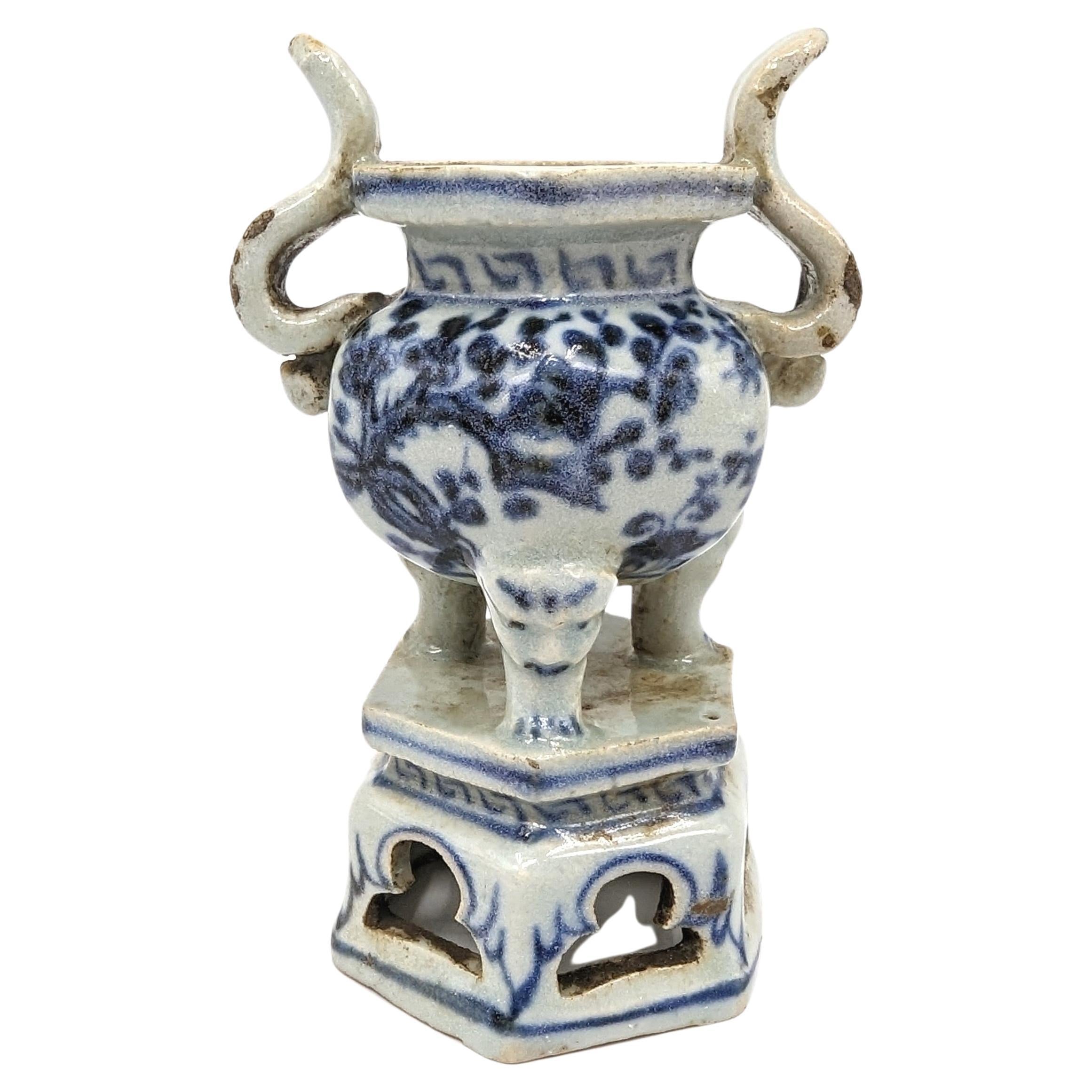 This antique Ming Chinese tripod censer is a masterful example of blue and white porcelain artistry. The censer features a well-proportioned body that is underglaze decorated with the 