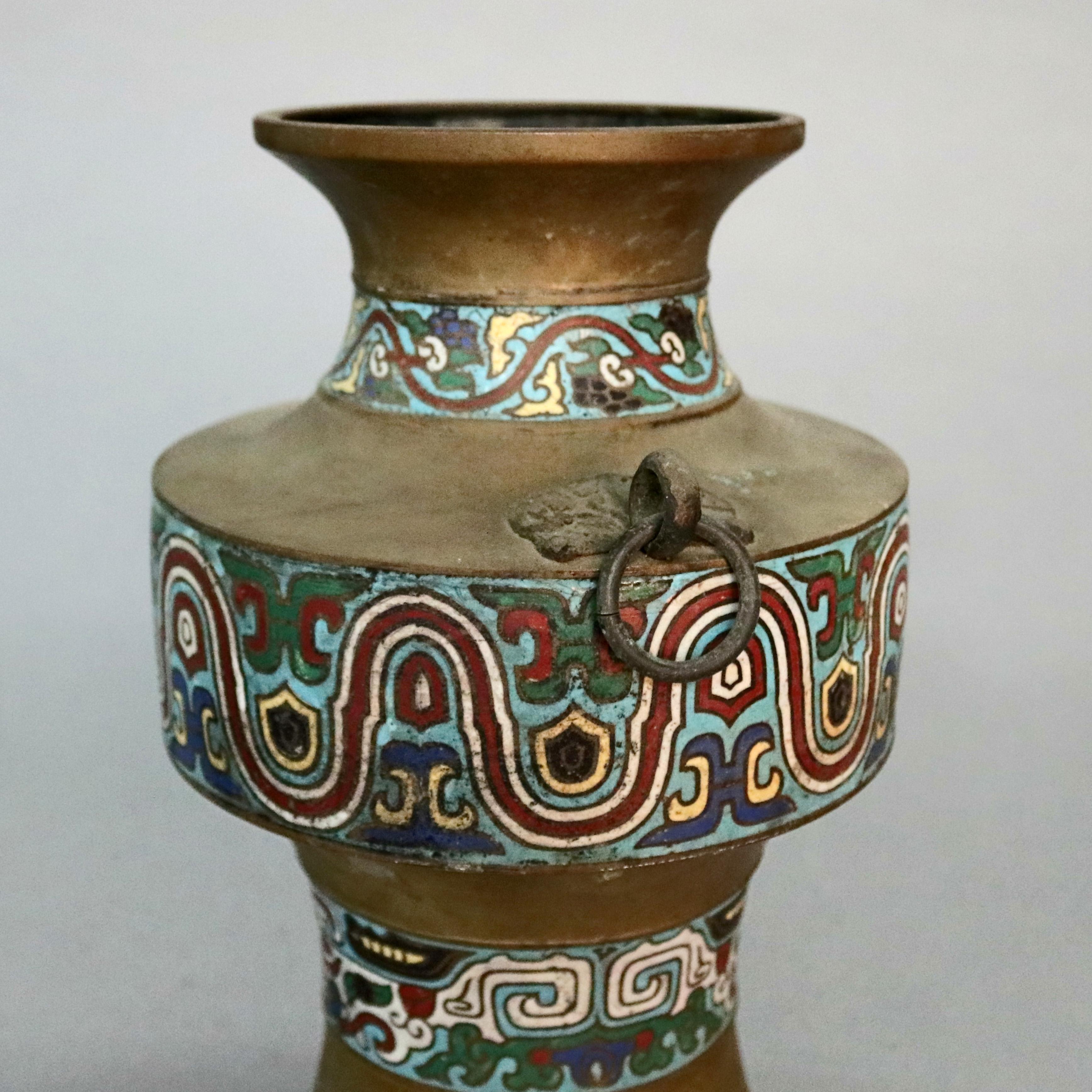 An antique Chinese cloisonné vase offers bronze vessel having bands of hand enameled repeating geometric stylized foliate patterns and flanking ring handles, circa 1920.

Measures: 11.75