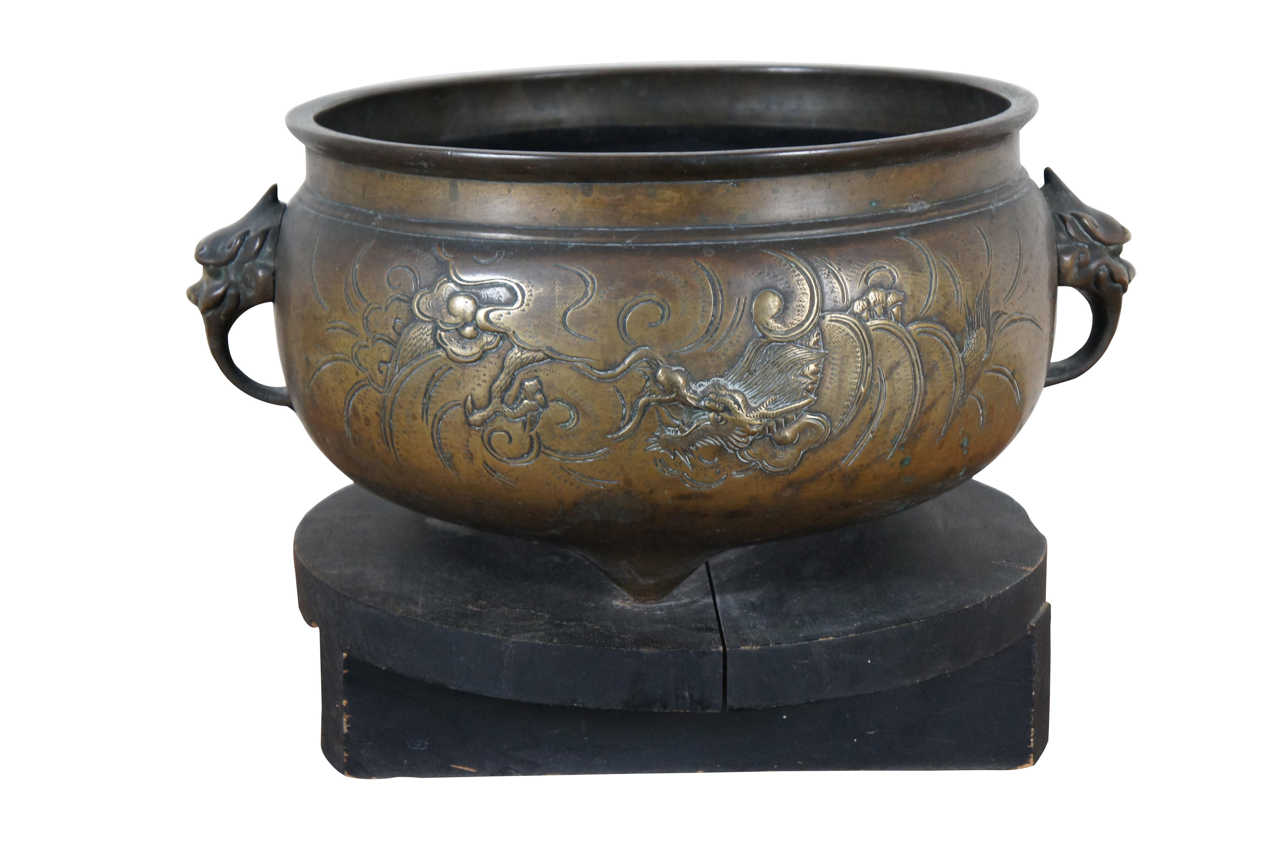 A large and impressive antique Chinese bronze Temple censer bowl on stand featuring a Phoenix on one side and Dragon on the other, with Feng Shui beast head handles and wood stand.

Dimensions:
17