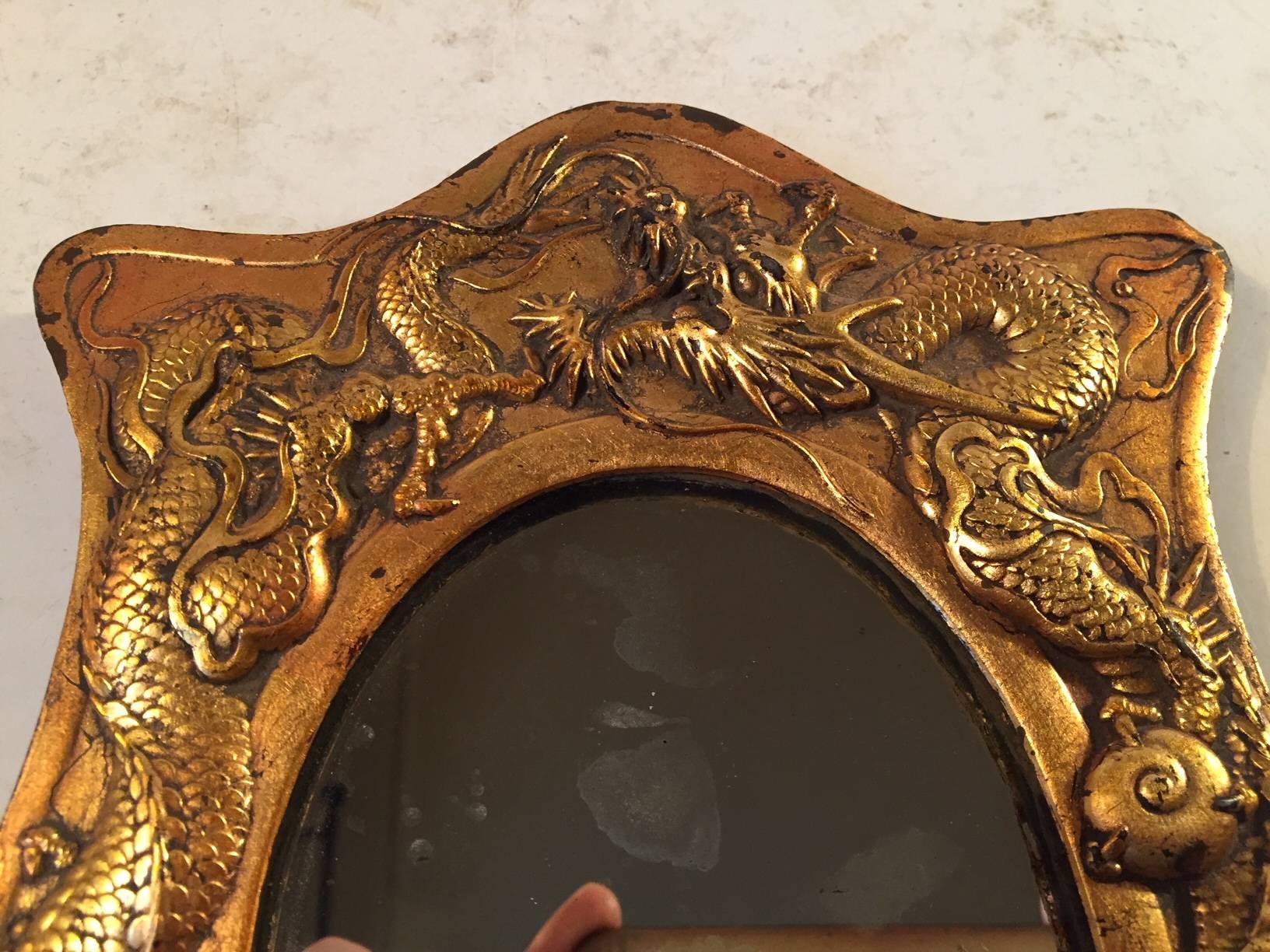 A very detailed bronze mirror with raised motifs of dragons to the frame. It is a small mirror suited for make-up or decoration. It was manufactured in Japan between 1870-1900 and it was probably intended as a picture/photo frame. The measurements