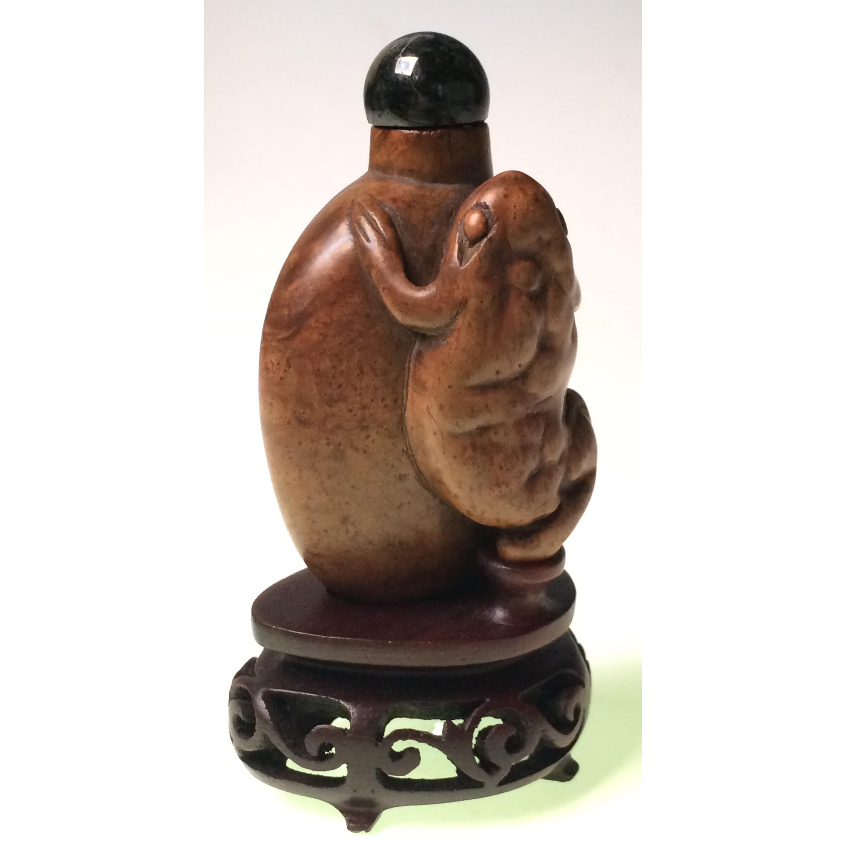 Antique Chinese burl wood snuff bottle with a large three legged toad on the front in high relief, overall oval shape with oval foot rim and countersunk flat base, adequately hollowed, small round neck, jade stopper, stained and carved organic