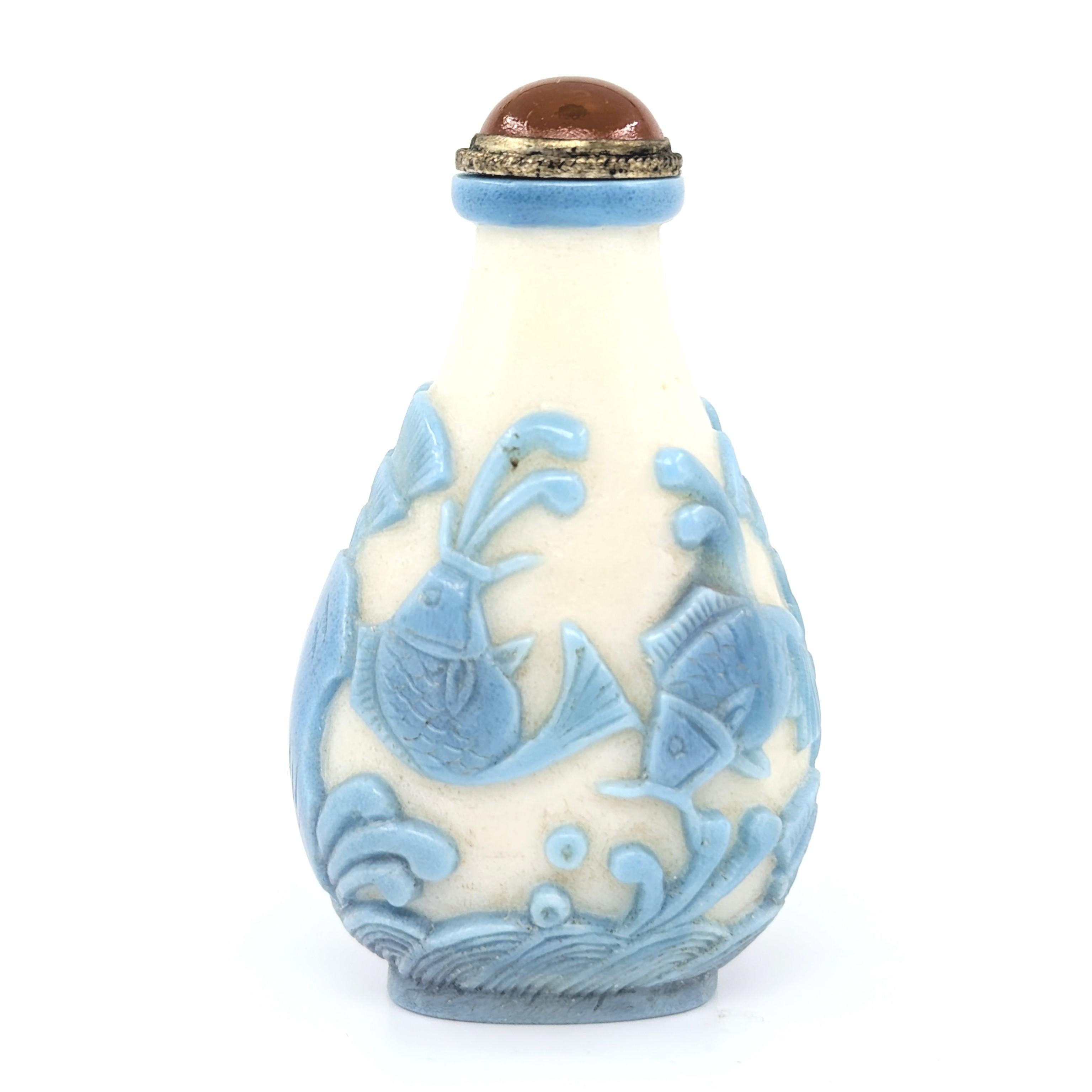 Presenting a splendid antique Chinese snuff bottle, a fine example late Qing dynasty artistry. This piece features a delicate light blue glass overlay, gracefully carved in relief on a milk-white glass ground, creating a serene and harmonious visual