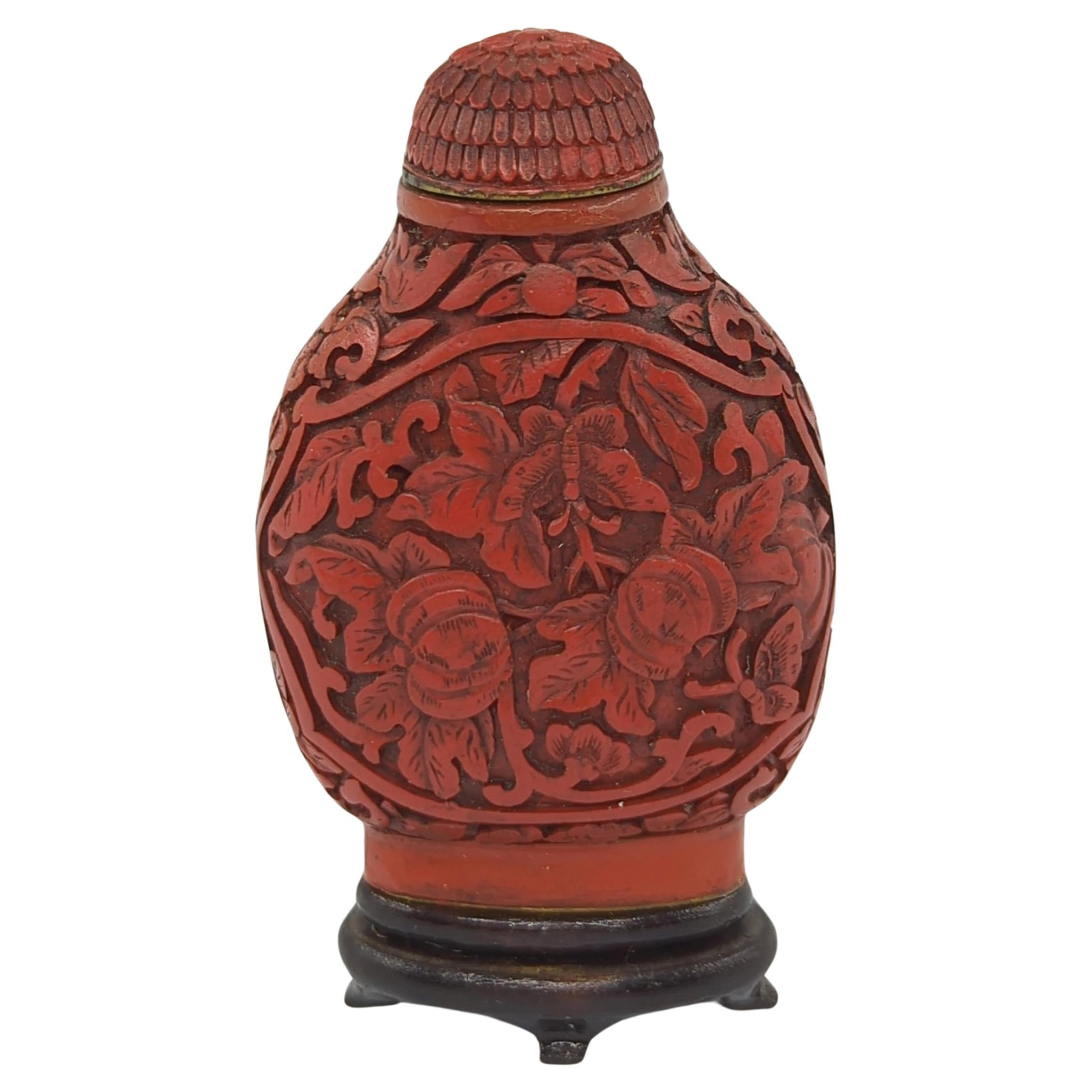 Antique Chinese red cinnabar lacquer snuff bottle, finely carved with melons, butterflies and bats, matching cinnabar stopper and 2 character Daoguang mark to base, comes with a hardwood stand

19c Qing Dynasty
