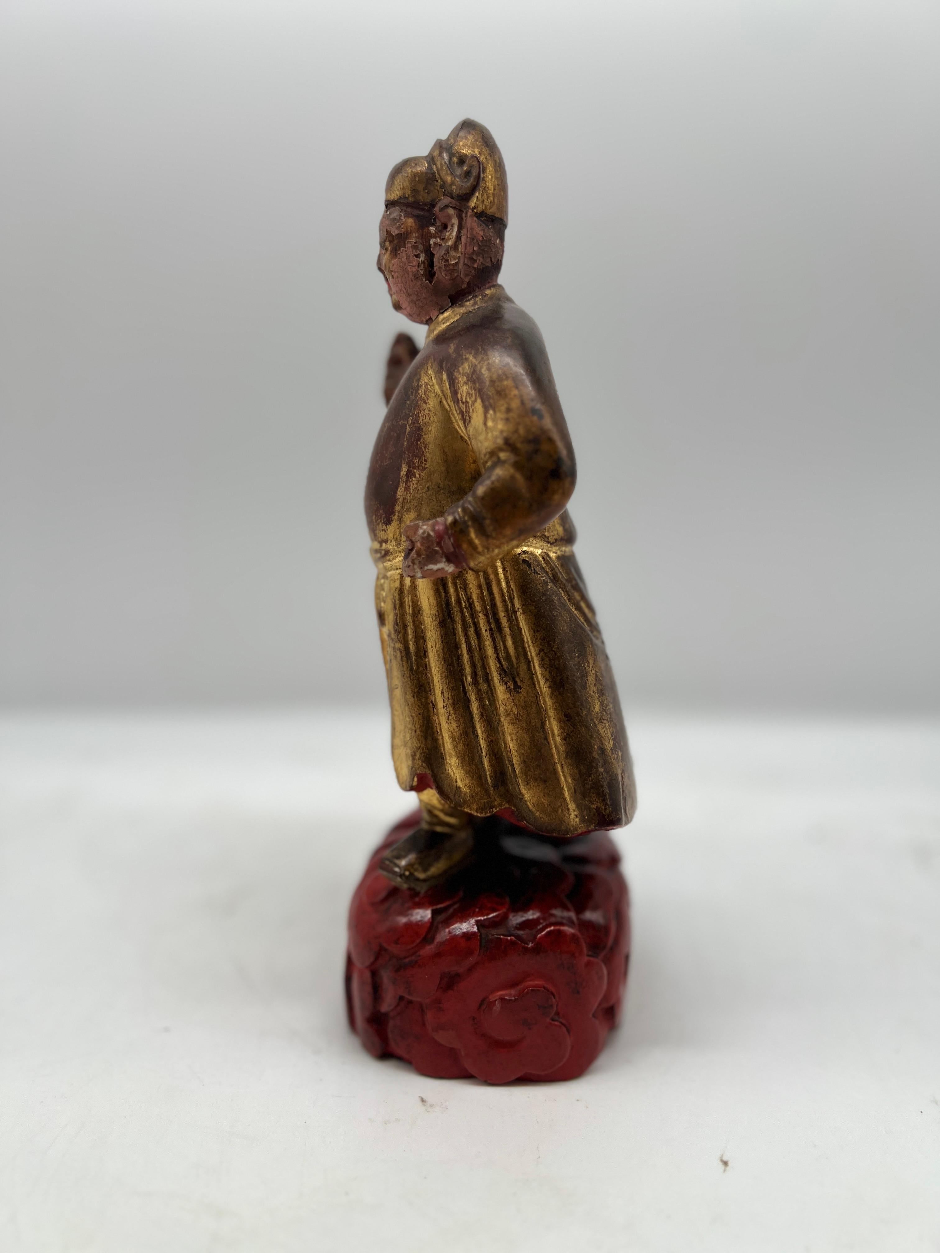 This exquisite antique Chinese figure, carved from wood and adorned with gilding and polychrome decoration, showcases the exceptional artistry of traditional Chinese craftsmanship. Likely originating from a temple or shrine, the figure embodies the