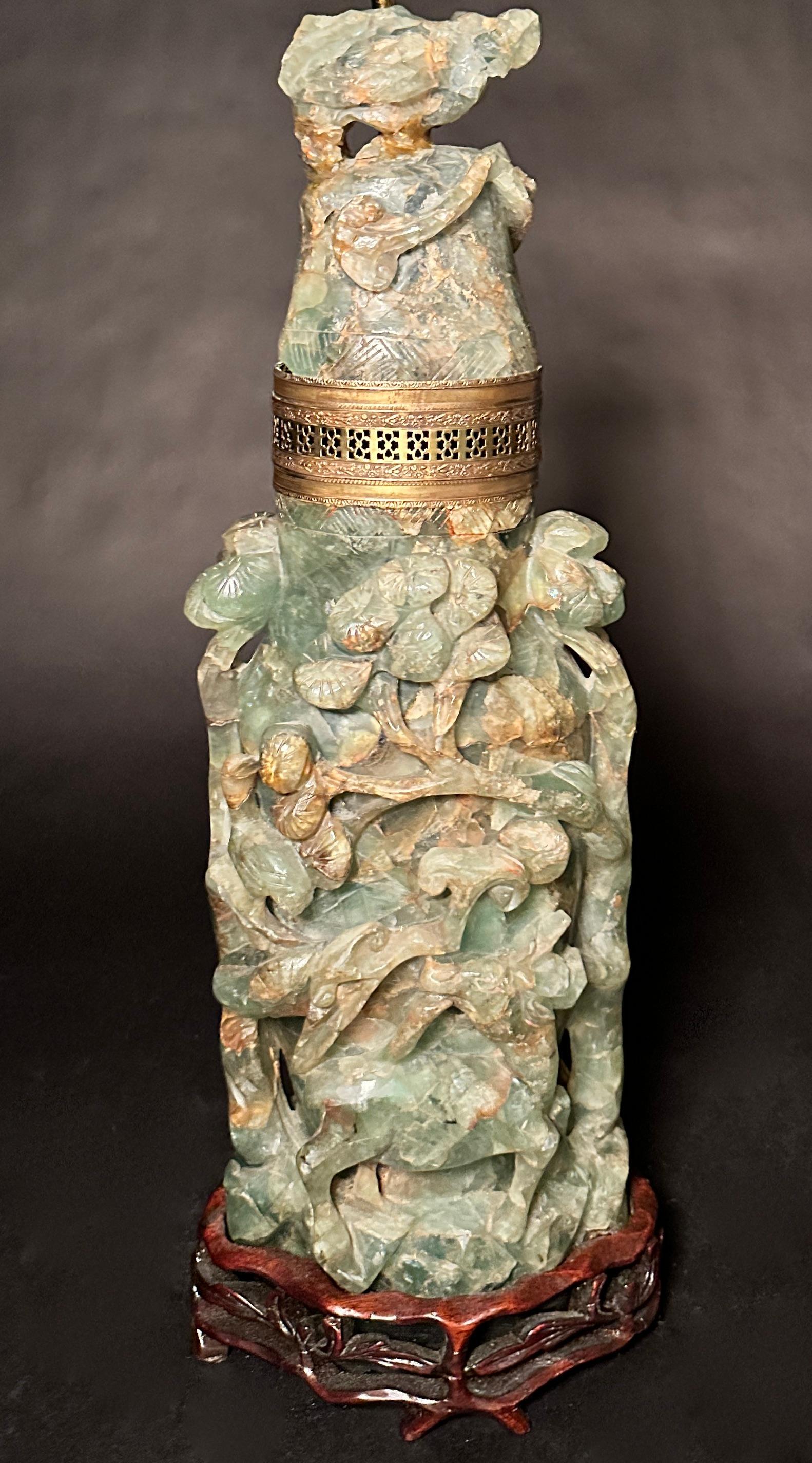 Lampe chinoise en pierre sculptée montée sur une base en bois de rose sculpté. La pierre sculptée est souvent appelée jadéite ou quartz, mais elle appartient en fait à la famille des fluorines. Ce pied de lampe a été sculpté en Chine à la fin du