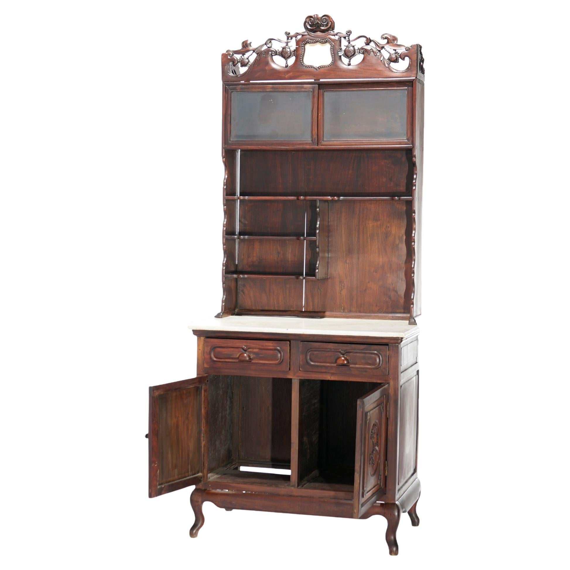 An antique Chinese display cabinet offers hardwood construction with pierced foliate crest over shelving unit which surmounts lower marble top case with two upper shelves and double foliate carved door cabinet, raised on cabriole legs,