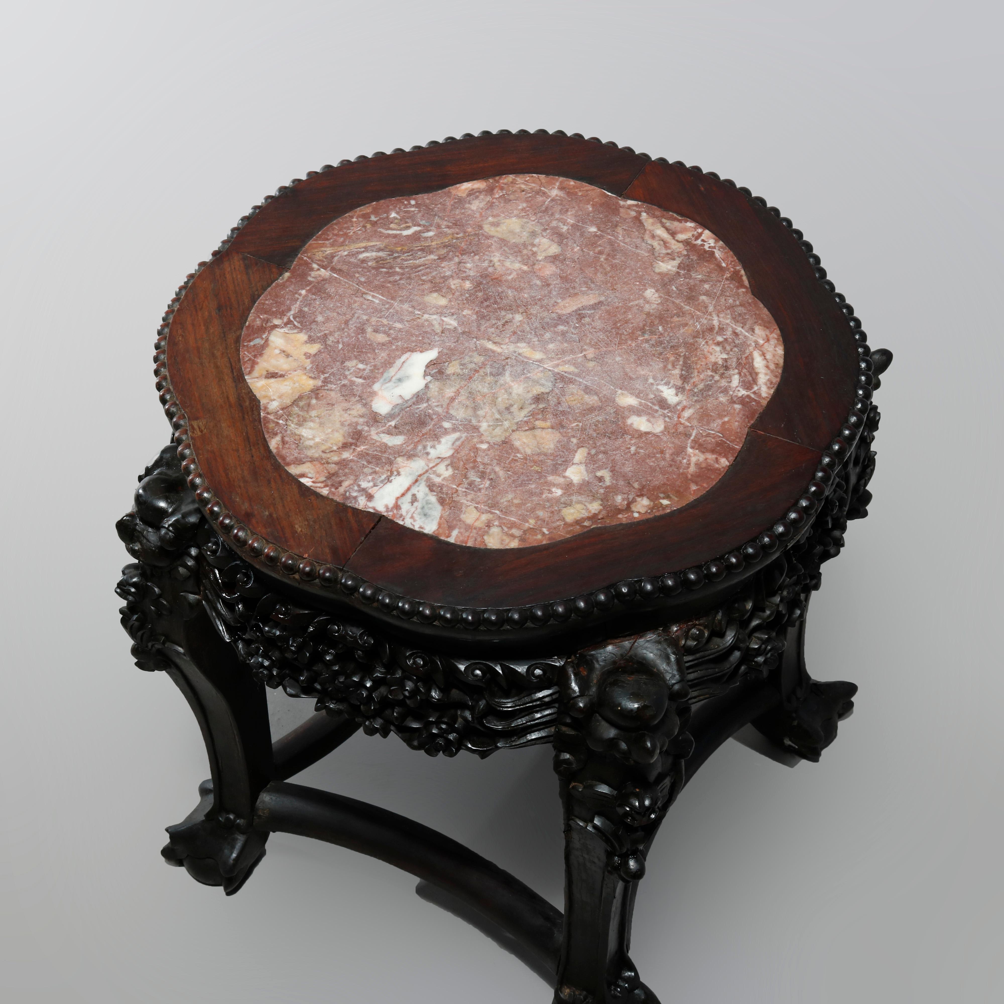 An antique Chinese plant stand offers shaped top with inset marble top surmounting hardwood frame with foliate deeply carved skirt raised on legs with stylized claw and ball feet, c1920.

Measures: 18.25