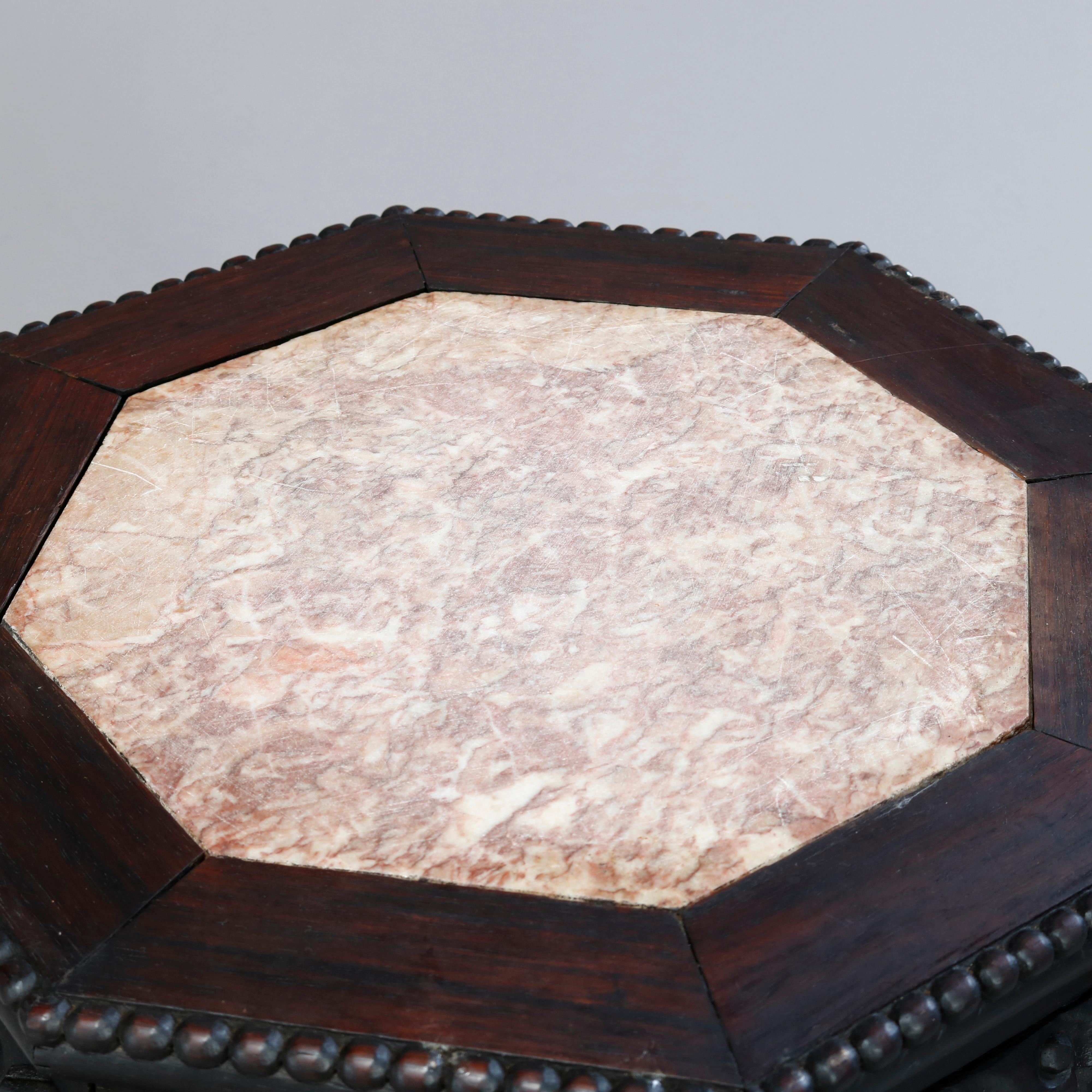 An antique Chinese plant stand offers octagonal form with inset marble top surmounting hardwood frame with foliate deeply carved skirt raised on legs with stylized claw and ball feet, c1920.

Measures: 18.5