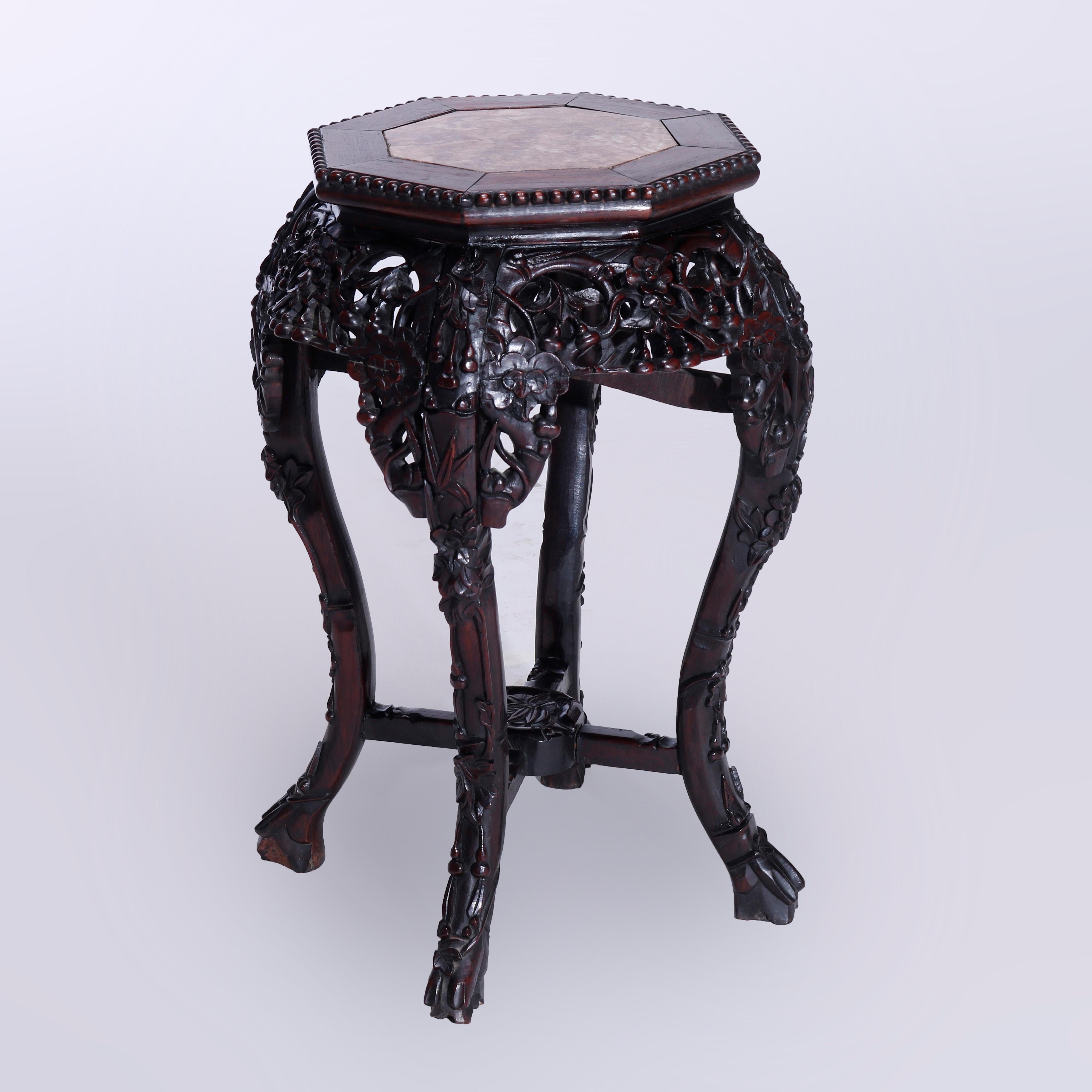 An antique Chinese side table or plant stand offers inset marble top with beaded trimming over reticulated scroll and foliate carved rosewood base having cabriole legs terminating in stylized paw feet with cross stretcher having floral carved