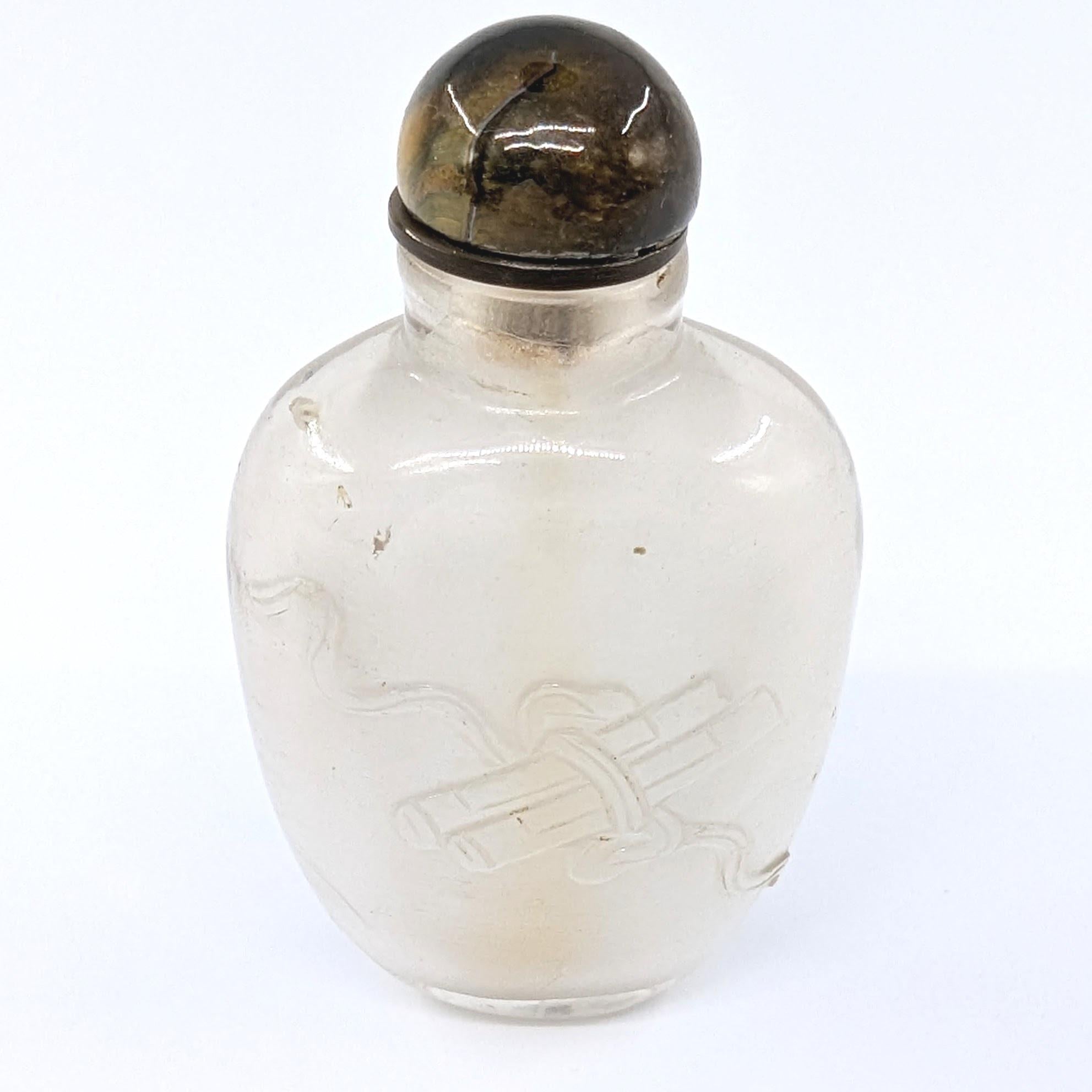 Antique Chinese rock crystal snuff bottle, finely carved in low relief with a lotus scene to one side and a scroll in flowing ribbons to the other, with tiger's eye stopper and bone spoon 

19c Qing Dynasty