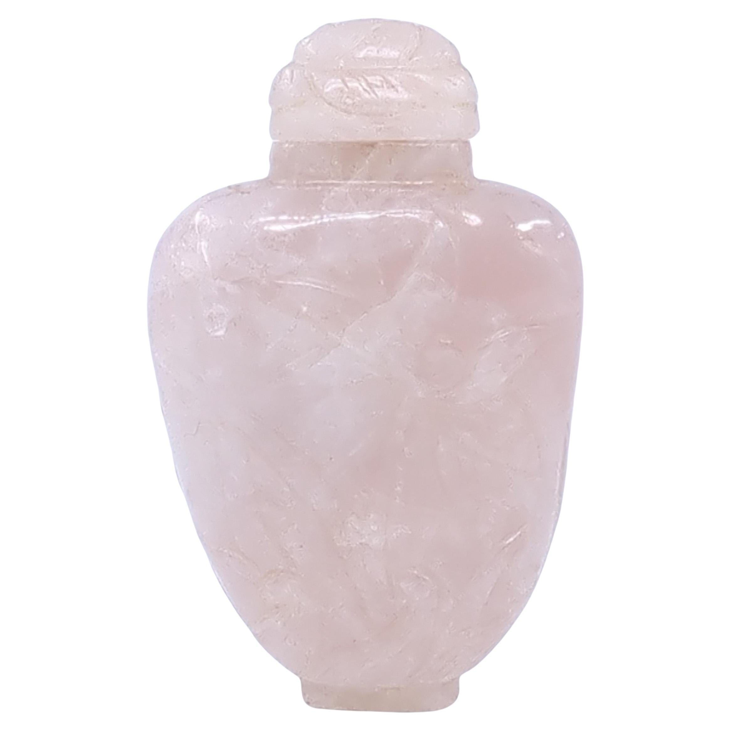 Ce flacon de tabac à priser en quartz rose sculpté du milieu du XXe siècle, période 5/6/7, est un objet délicat et exquis qui reflète l'esthétique raffinée et l'habileté de l'artisanat de l'époque. Le flacon est taillé dans un seul morceau de quartz
