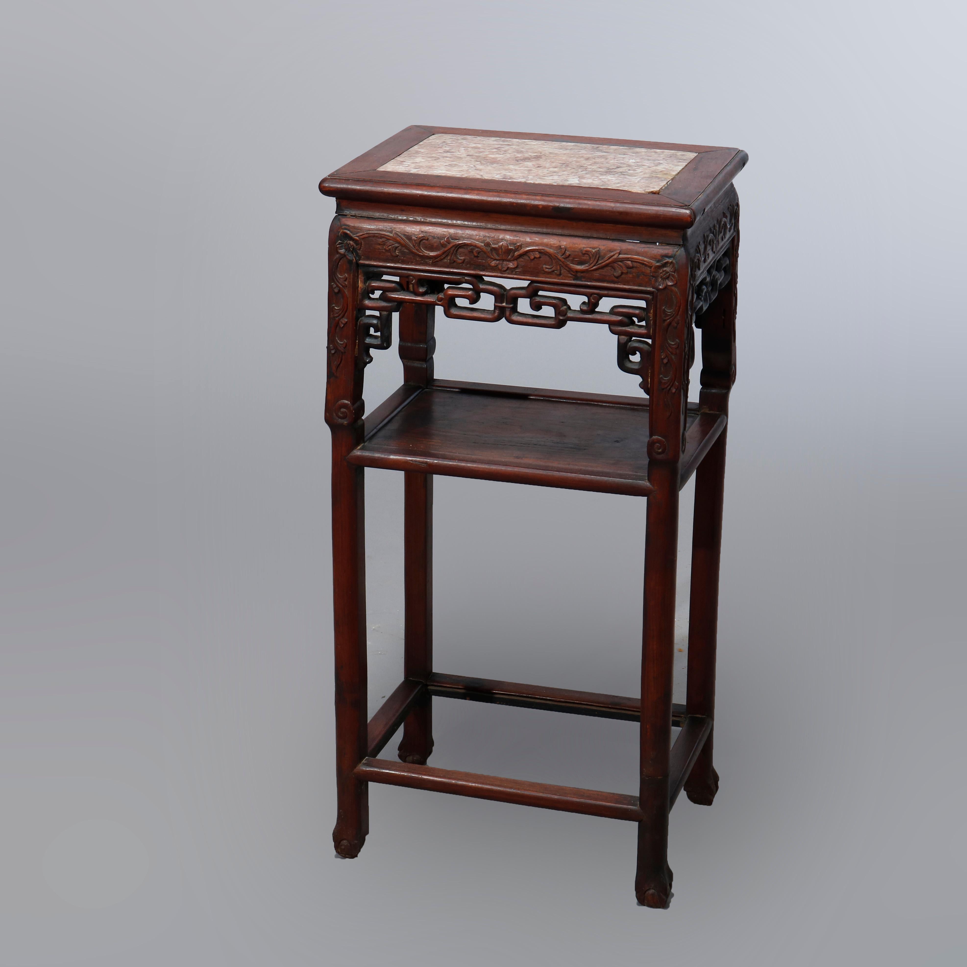An antique Chinese plant stand offers rosewood construction with inset marble top over frame with foliate carved and pierced skirt over lower display shelf and having stylized claw and ball feet, 19th century

Measures: 32.75