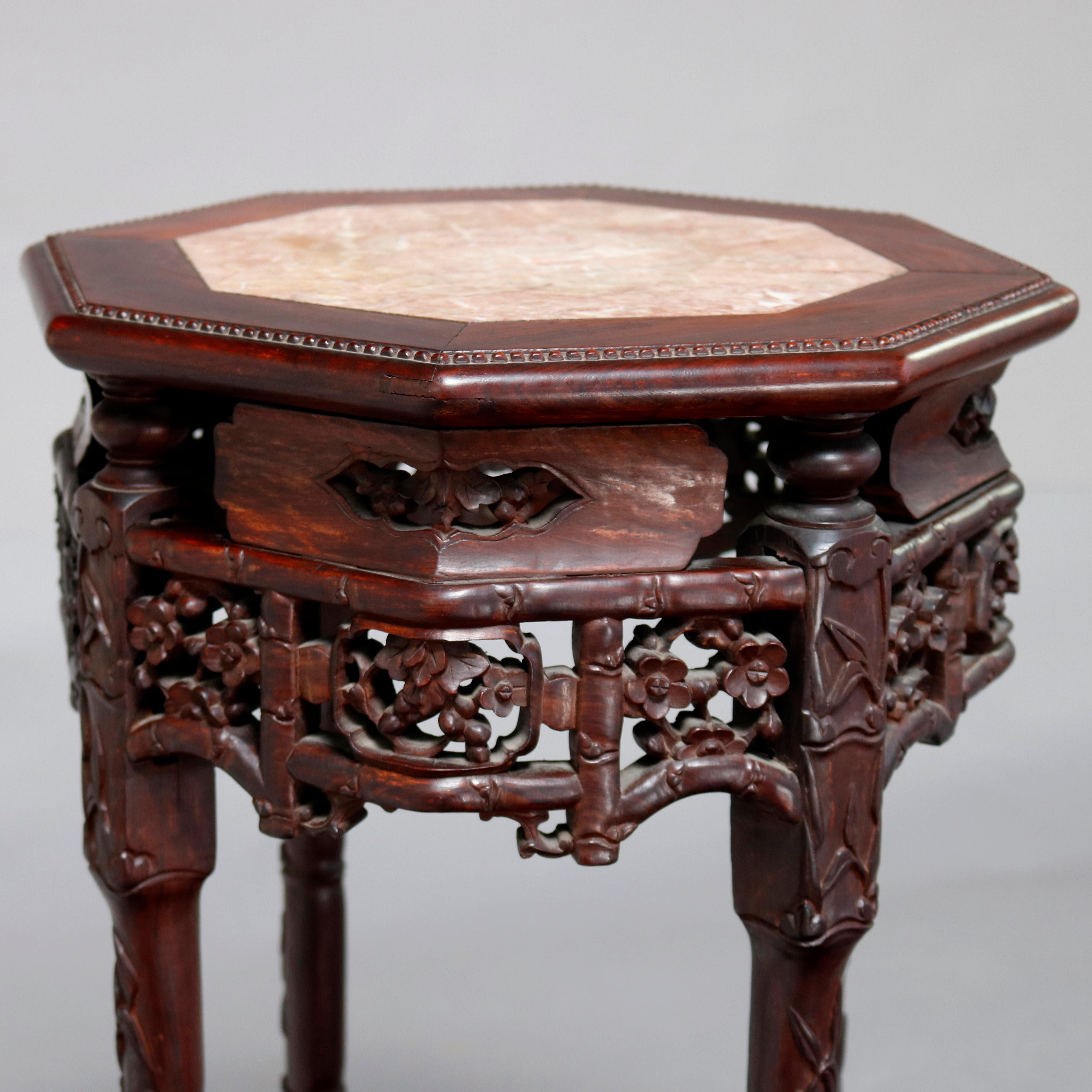 An antique Chinese sculpture stand offers carved rosewood base in octagonal form and having inset marble top with beaded bordering, pierced foliate and floral skirt, raised on carved legs with lower pierced star and floral display shelf, circa