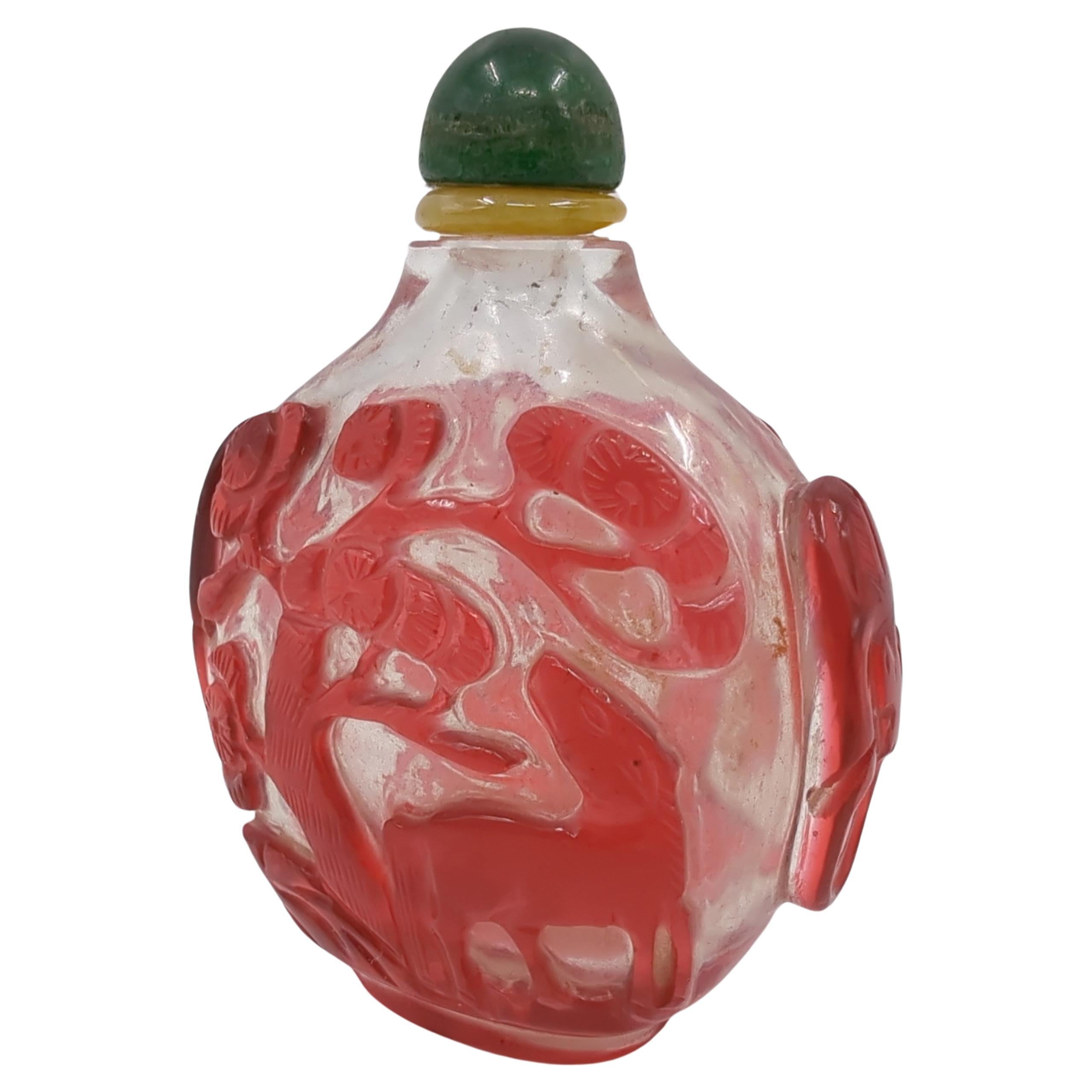 Antique late Qing Dynasty ruby red glass overlay clear ground snuff bottle, hand carved with a horse in a treed meadow scene to each side, carved elephant  head and ring taoties to shoulders, having a fixed green hard stone stopper and a jadeite