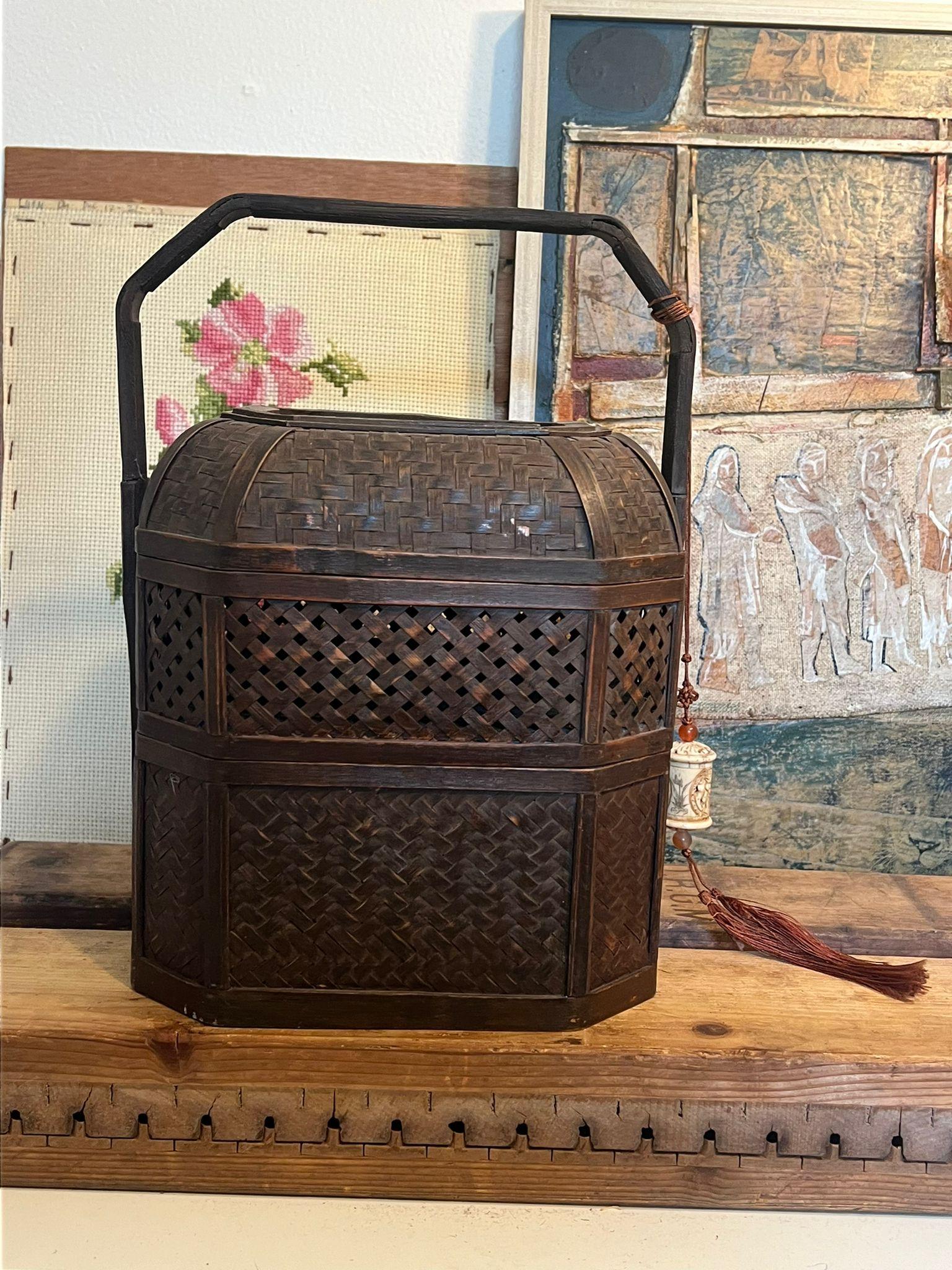 Ce panier décoratif en osier, dont on pense qu'il a été utilisé comme boîte à linge, comporte plusieurs couches à l'intérieur et un charme sculpté unique attaché à l'anse. Cette pièce présente une belle patine et du caractère. Condition Vintage