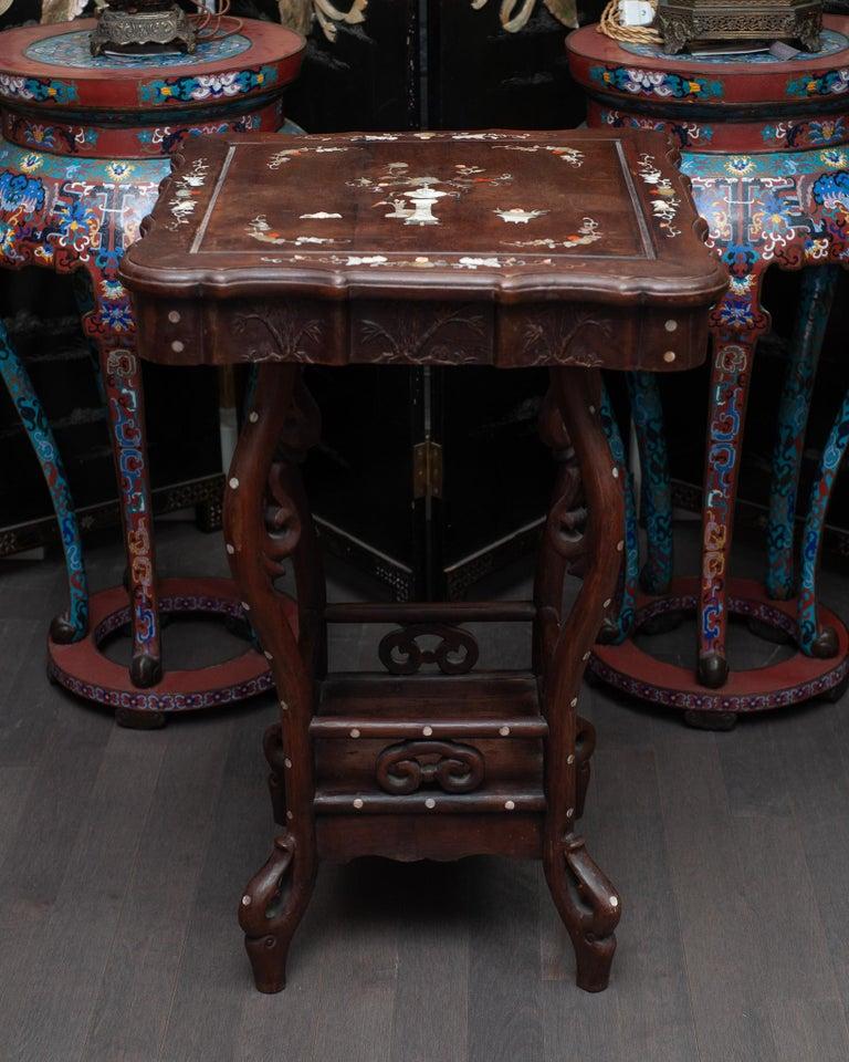 Cette rare table antique chinoise témoigne d'un savoir-faire magistral, avec son bois sculpté de façon complexe et ses délicates incrustations de nacre. Les sculptures élaborées présentent des motifs chinois traditionnels, ajoutant de la profondeur