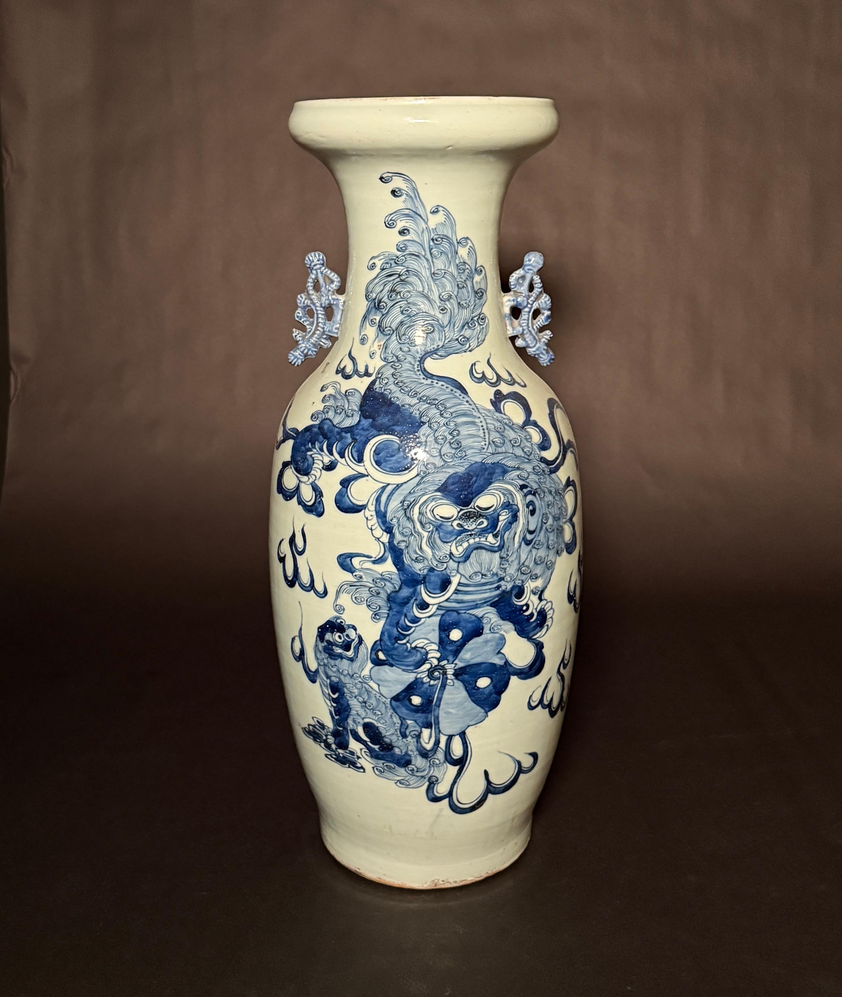  Un grande vaso da terra cinese del XIX secolo con fondo celadon e decorazioni blu e bianche sottosmalto sul corpo. La decorazione sottosmalto raffigura un grande leone Foo sopra un cane Foo più piccolo. Al collo sono stati applicati dei manici