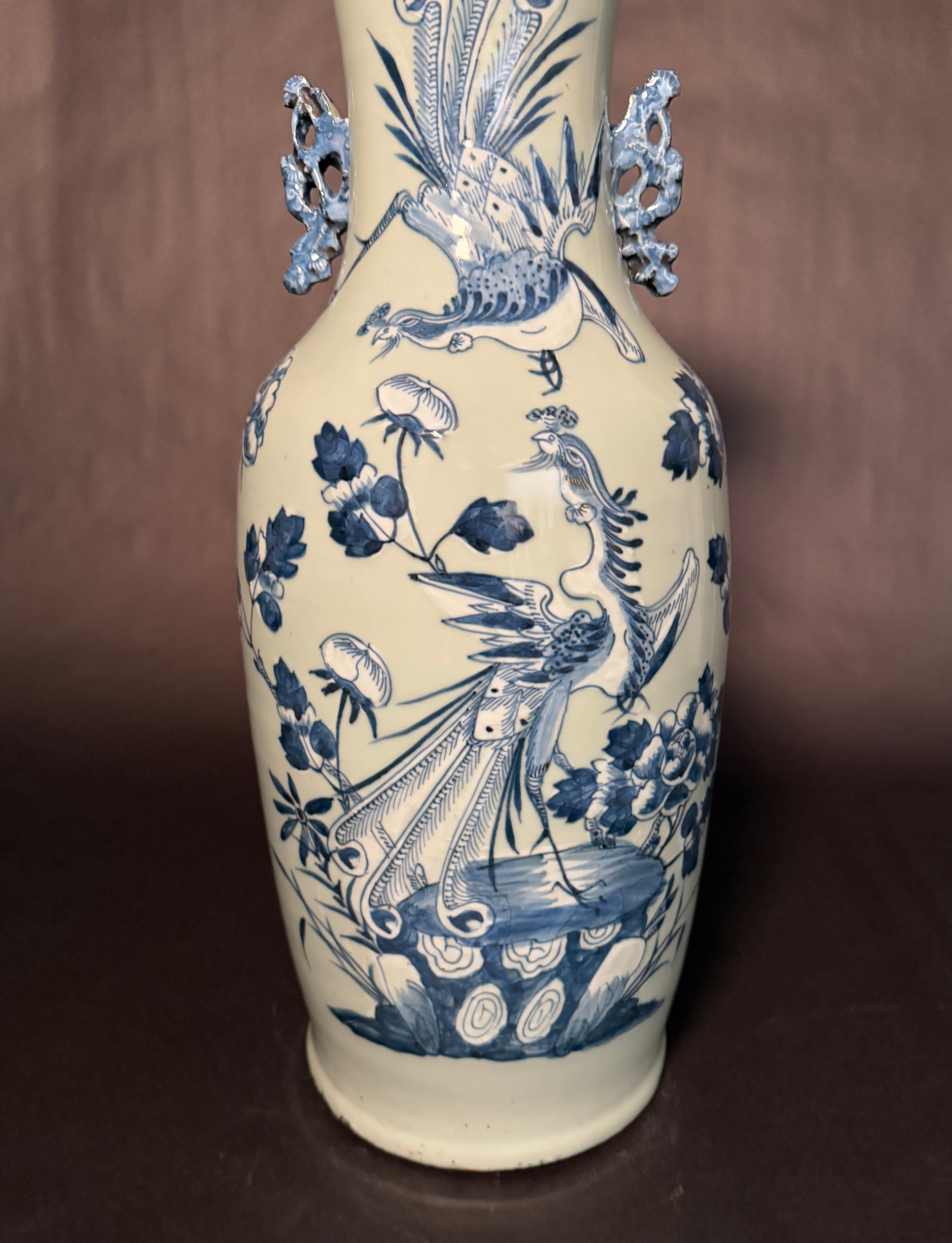 Un grande vaso da terra cinese del XIX secolo con fondo celadon e decorazioni blu e bianche sottosmalto sul corpo. La decorazione sottosmalto raffigura un uccello Fenghuang (Fenice) al centro e un uccello simile più piccolo sopra. Maniglie