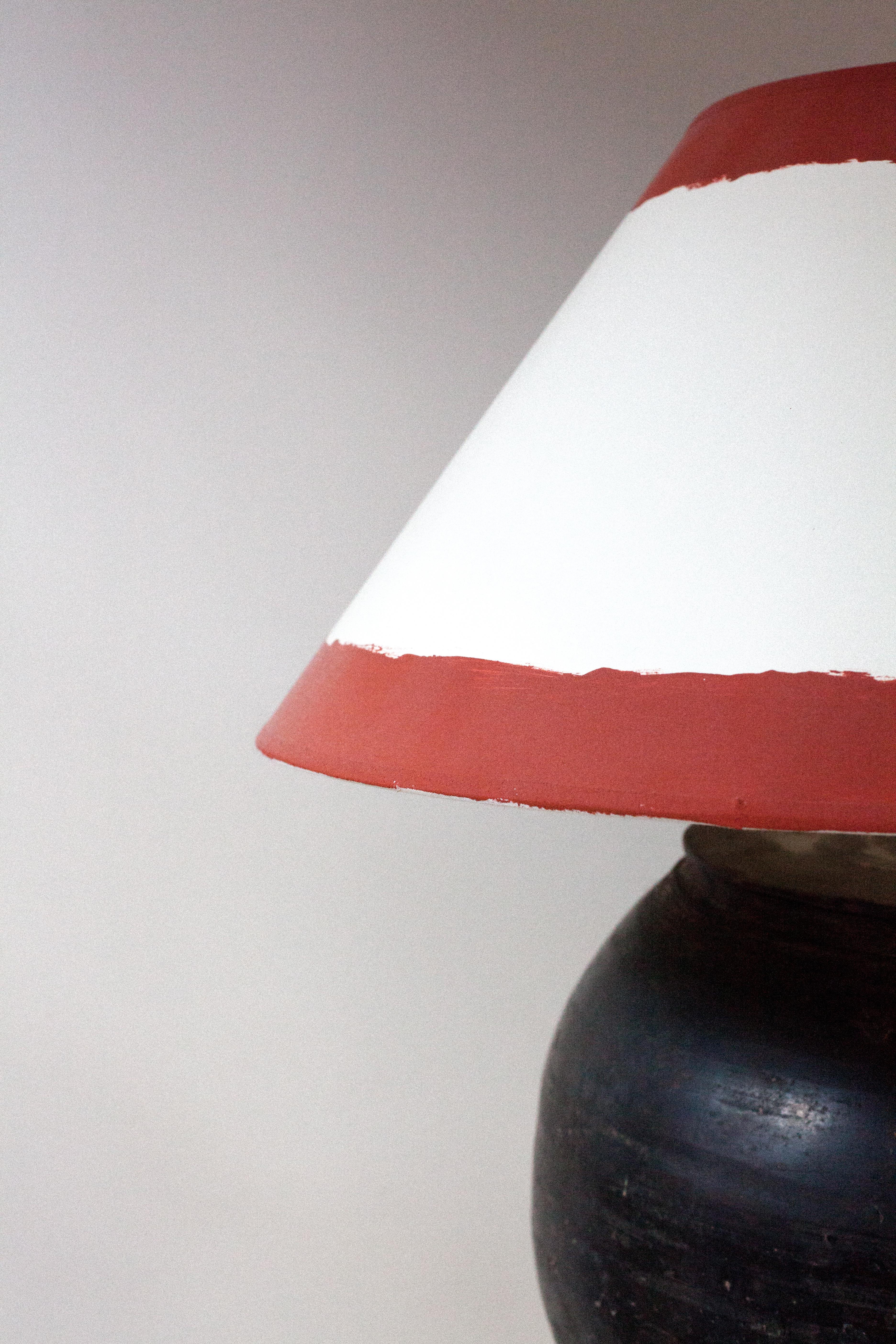 An earthenware ceramic jar later made into a lamp with E26 socket and Euro plug. A custom hand painted shade has been added consistent with the vernacular of the antique piece.