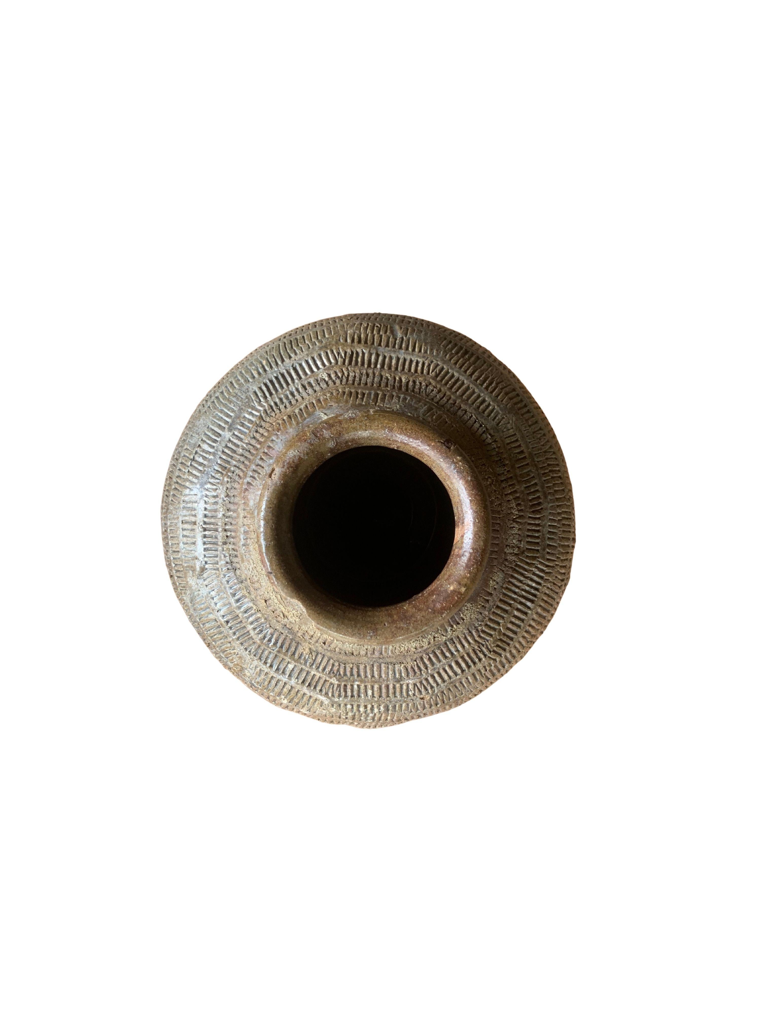 Questo vaso in ceramica cinese smaltata, risalente all'inizio del XIX secolo, veniva usato un tempo per mettere in salamoia gli alimenti. Presenta una finitura verde giada e una superficie esterna con una texture a coste. Un grande esempio di