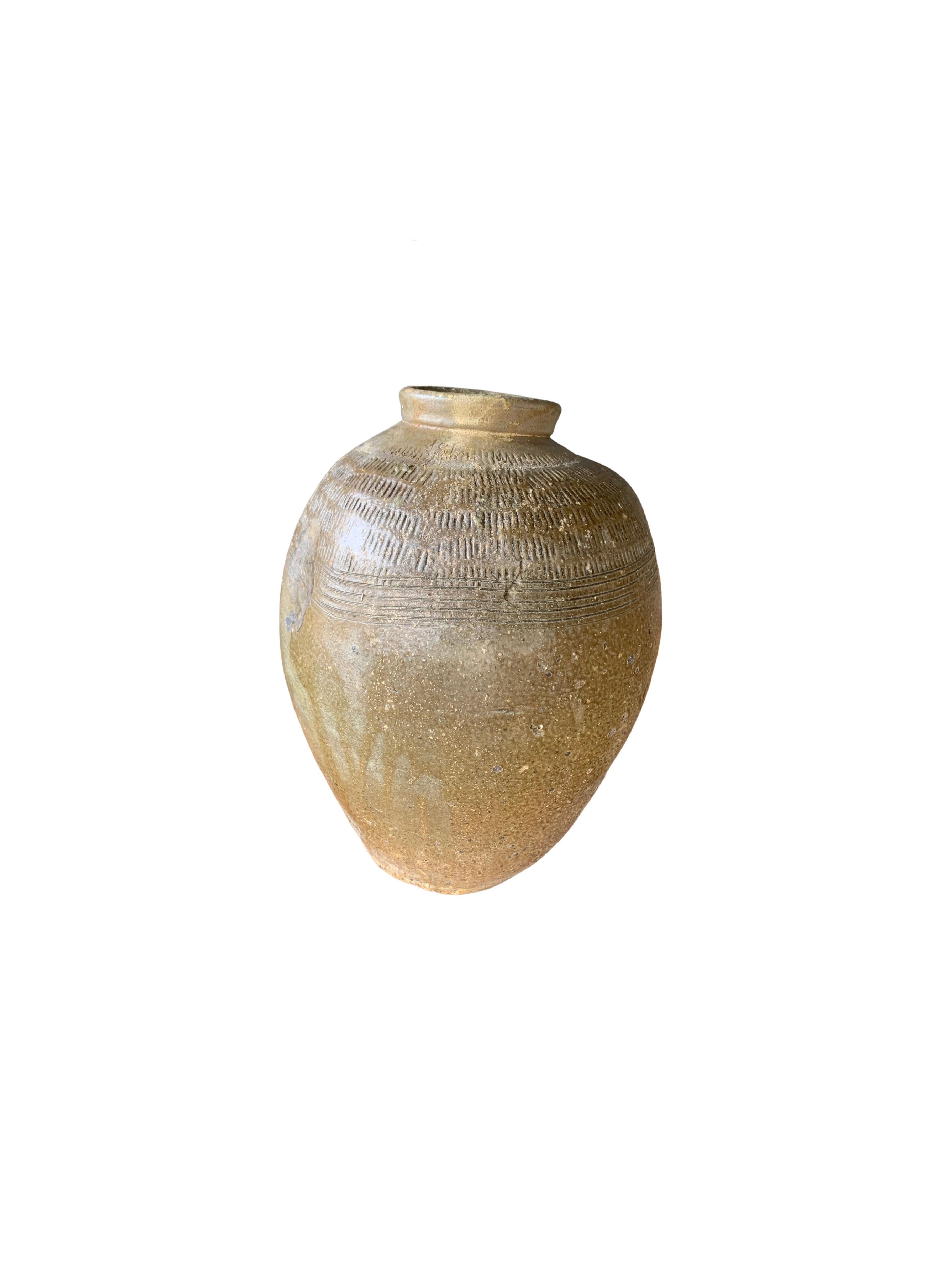 This glazed Chinese ceramic jar from the turn of the 19th century was once used for pickling foods. It features a jade green finish and outer surface that features a ribbed texture. This pot has a bent and indented shape which adds to its charm.