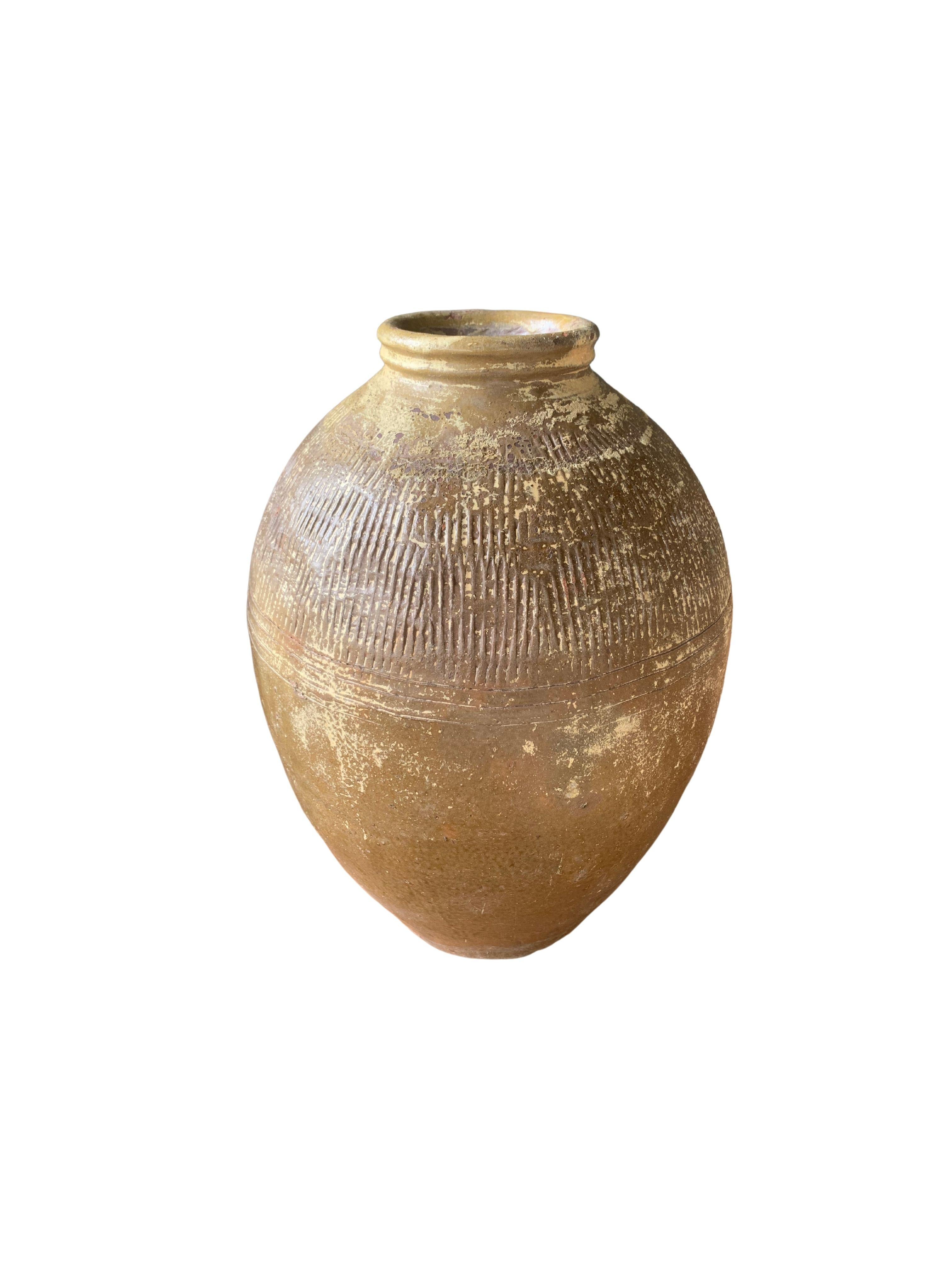 This glazed Chinese ceramic jar from the turn of the 19th Century was once used for pickling foods. It features a jade green finish and outer surface that features a ribbed texture. A great example of Chinese pottery, with its imperfections and