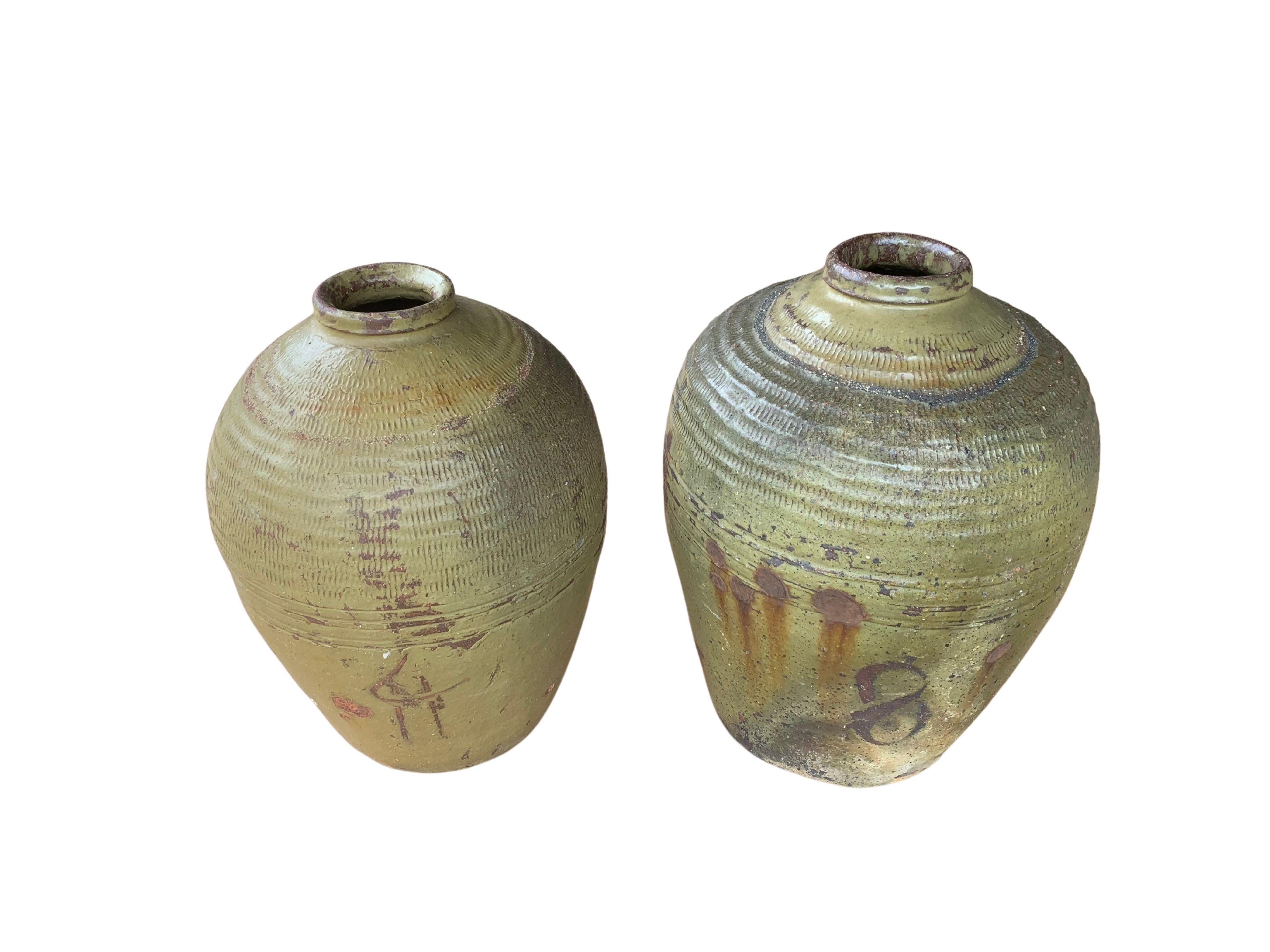 These glazed Chinese ceramic jars from the turn of the 19th century were once used for pickling foods. They feature a jade green finish and outer surface that features a ribbed texture. A great example of Chinese pottery, their imperfections and