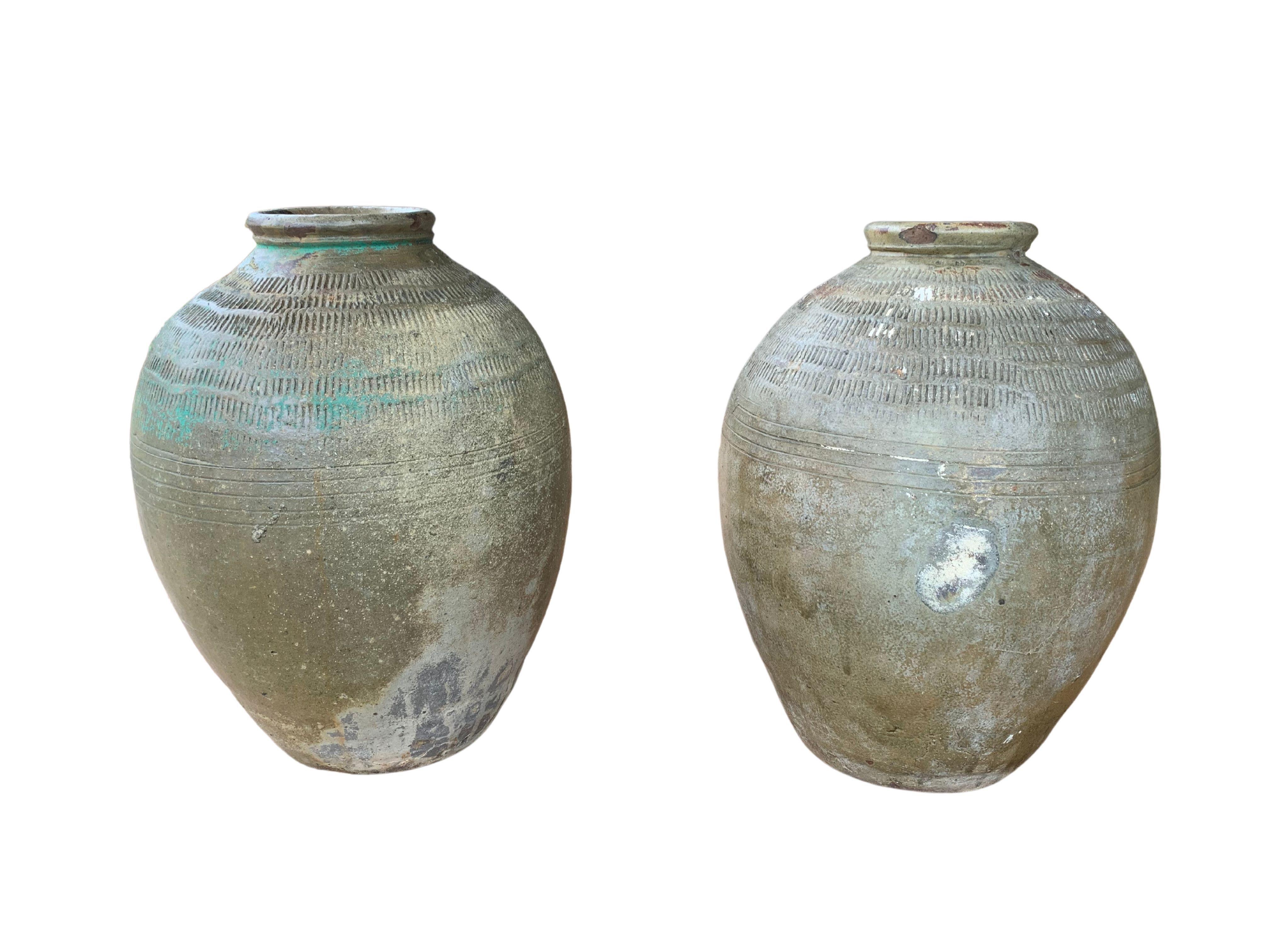 These glazed Chinese ceramic jars from the turn of the 19th Century were once used for pickling foods. They feature a jade green finish and outer surface that features a ribbed texture. A great example of Chinese pottery, their imperfections and