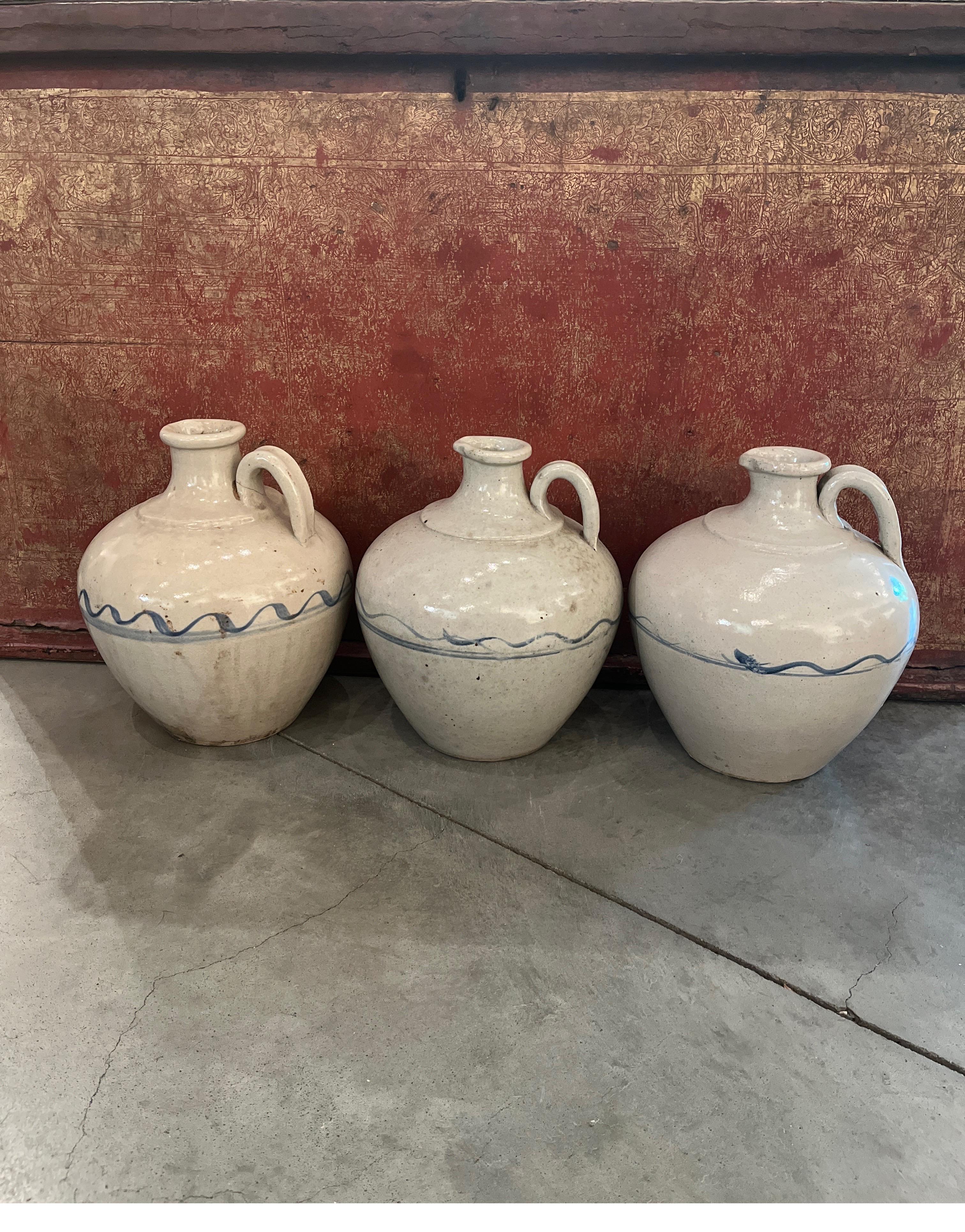 Beautifully glazed and hand painted 19th Century Chinese wine jars with simple blue designs against an eggshell background. These jars (priced and sold individually) look great as a set or on their own. Their light color, and the very