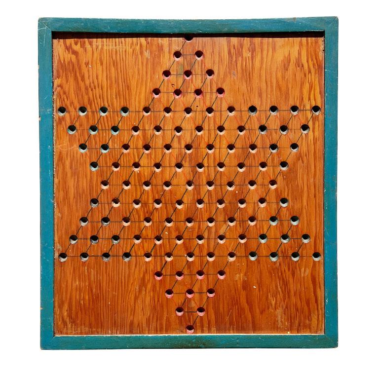 A solid wood antique Chinese Checkers game board. This piece is from Pennsylvania and was created in the early 1900s. It is created from wood and features hand-drilled holes for marbles, and beautiful blue paint on the sides and back. Bring this