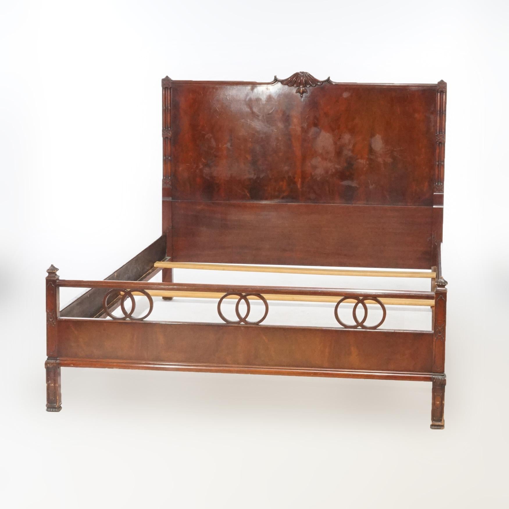 An antique double bed frame offers flame mahogany construction with headboard having carved crest and footboard with circular elements, c1930

 Measures - Headboard 46.5