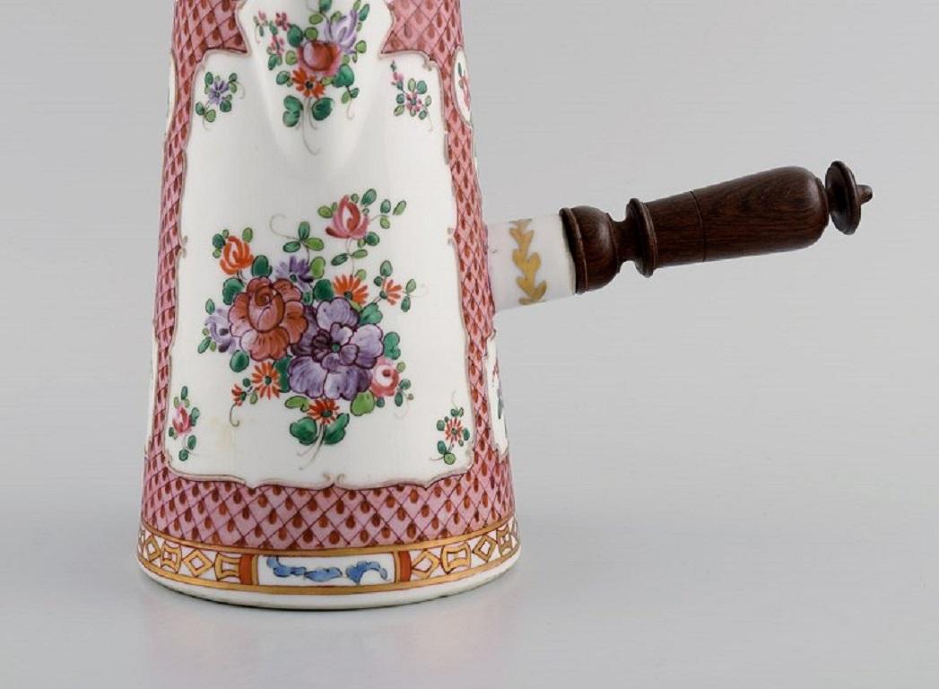 Antique Chinese chocolate pot in hand-painted porcelain with flowers and gold decoration. 
Handle and stirring rod in turned wood. 
18th / 19th century.
Measures: 22.5 x 19 cm (incl. Handle).
Stirring rod length: 29 cm.
In excellent