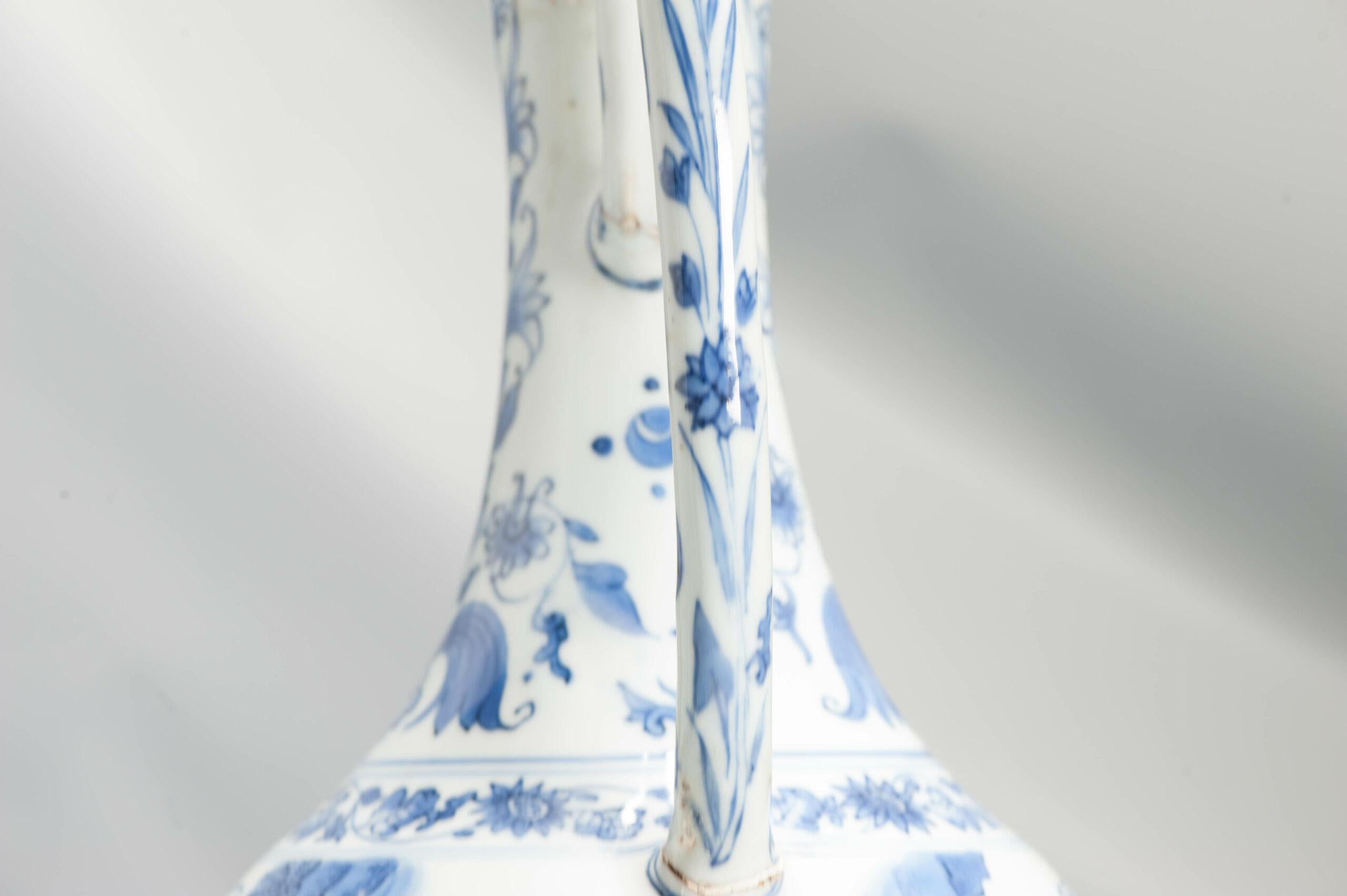 Une grande aiguière très joliment décorée en bleu sous glaçure. Le corps globulaire s'élève à partir d'un long col évasé décoré de tulipes et soutenu par une haute poignée. La décoration principale représente une rencontre entre deux savants