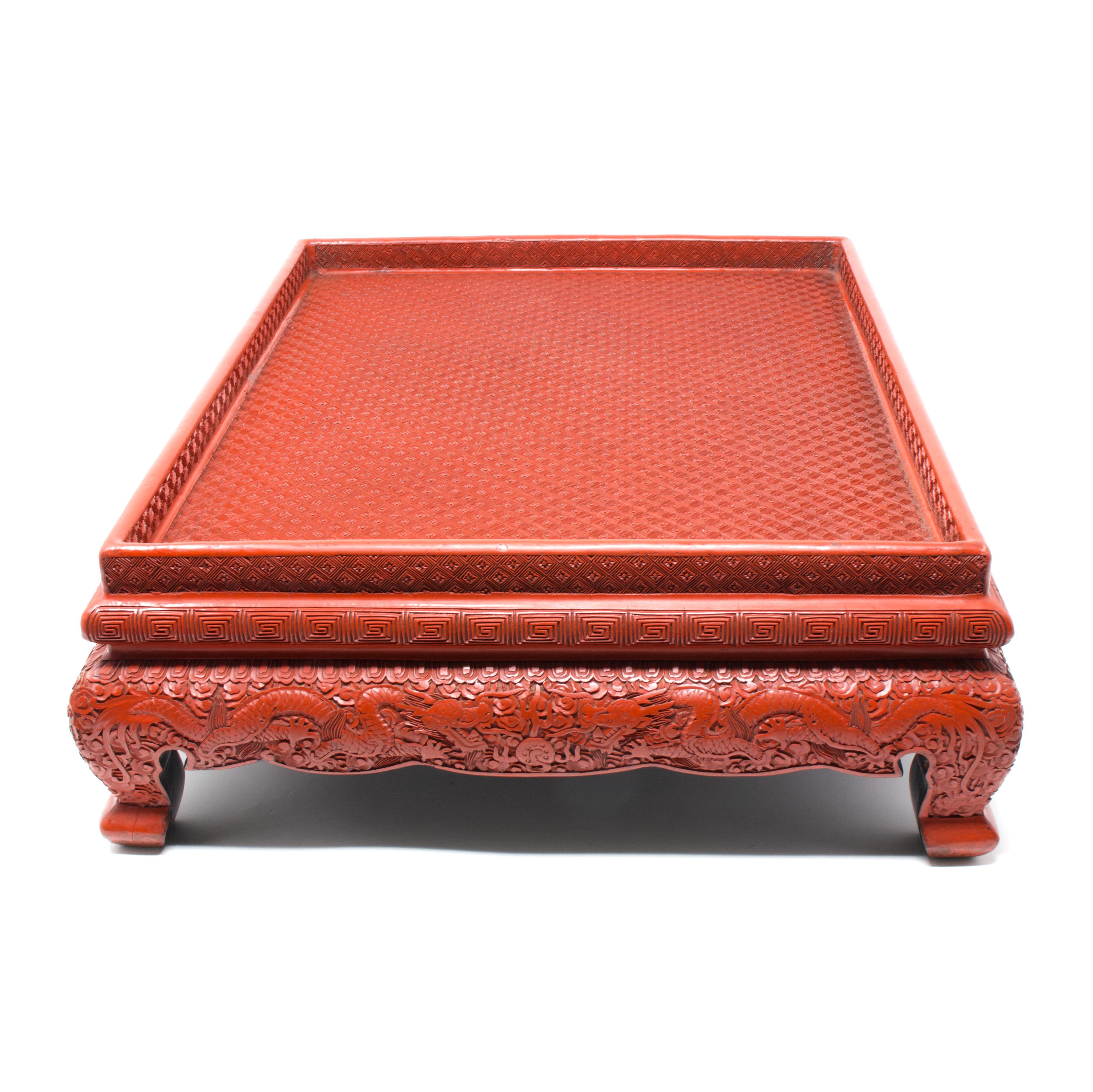 Antique Chinese Cinnabar Lacquer Tray/Stand with Dragon Design, Guangxu Period (1875-1908).
A dark vermillion red carved cinnabar lacquered Scholar’s tray on raised and footed supports. The top and sides of the tray carved in tight geometric