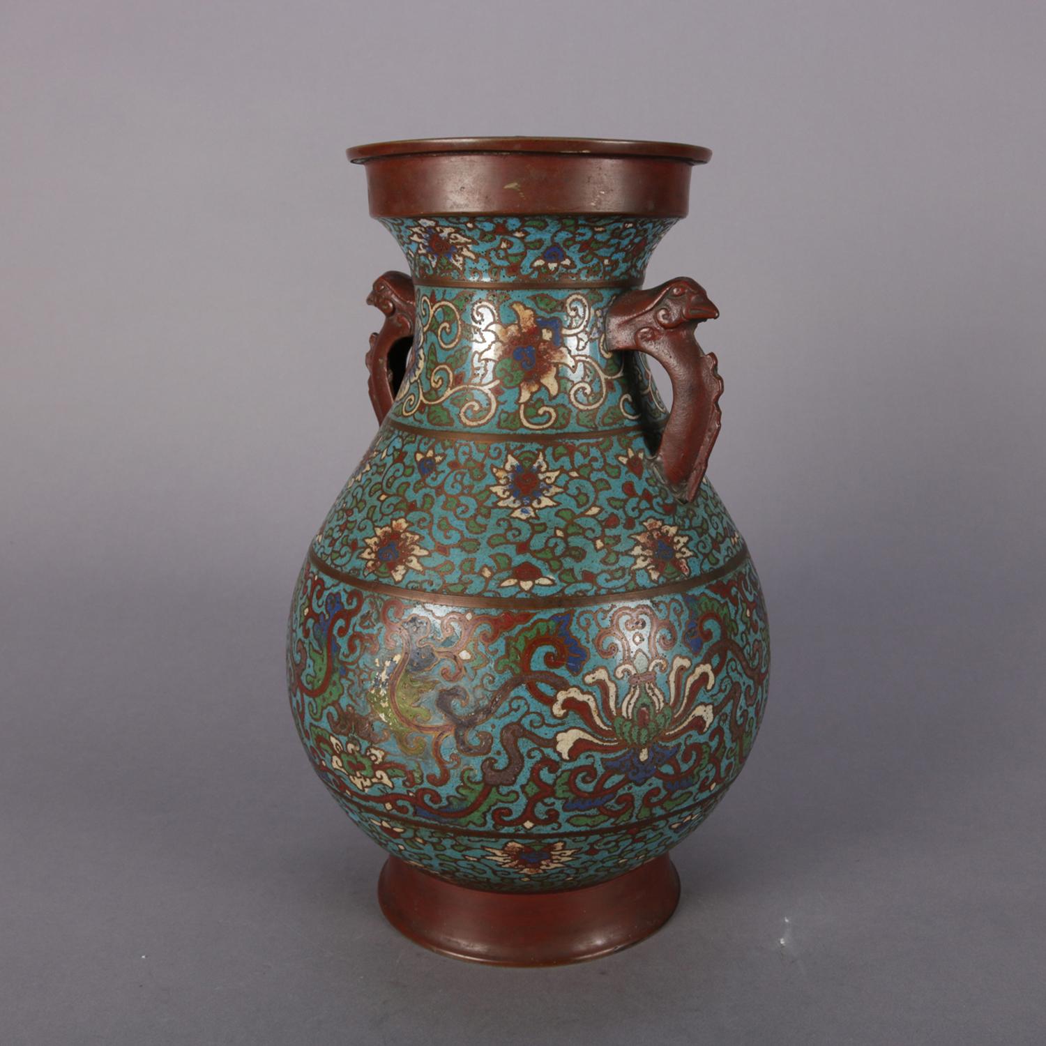 Antique Chinese Cloisonne double handle urn features bronze construction with floral and scroll enamelled decoration, circa 1900.

Measures: 14.5