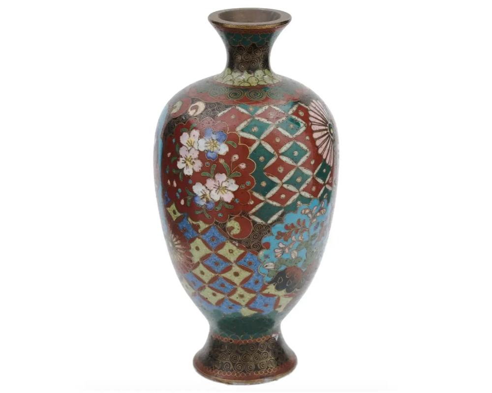 An antique Japanese, late Qing dynasty, enamel over brass vase. The amphora shaped vase is adorned with polychrome medallions depicting figures surrounded by floral, foliage, fan, swirl, and geometrical motifs made in the Cloisonne technique. The