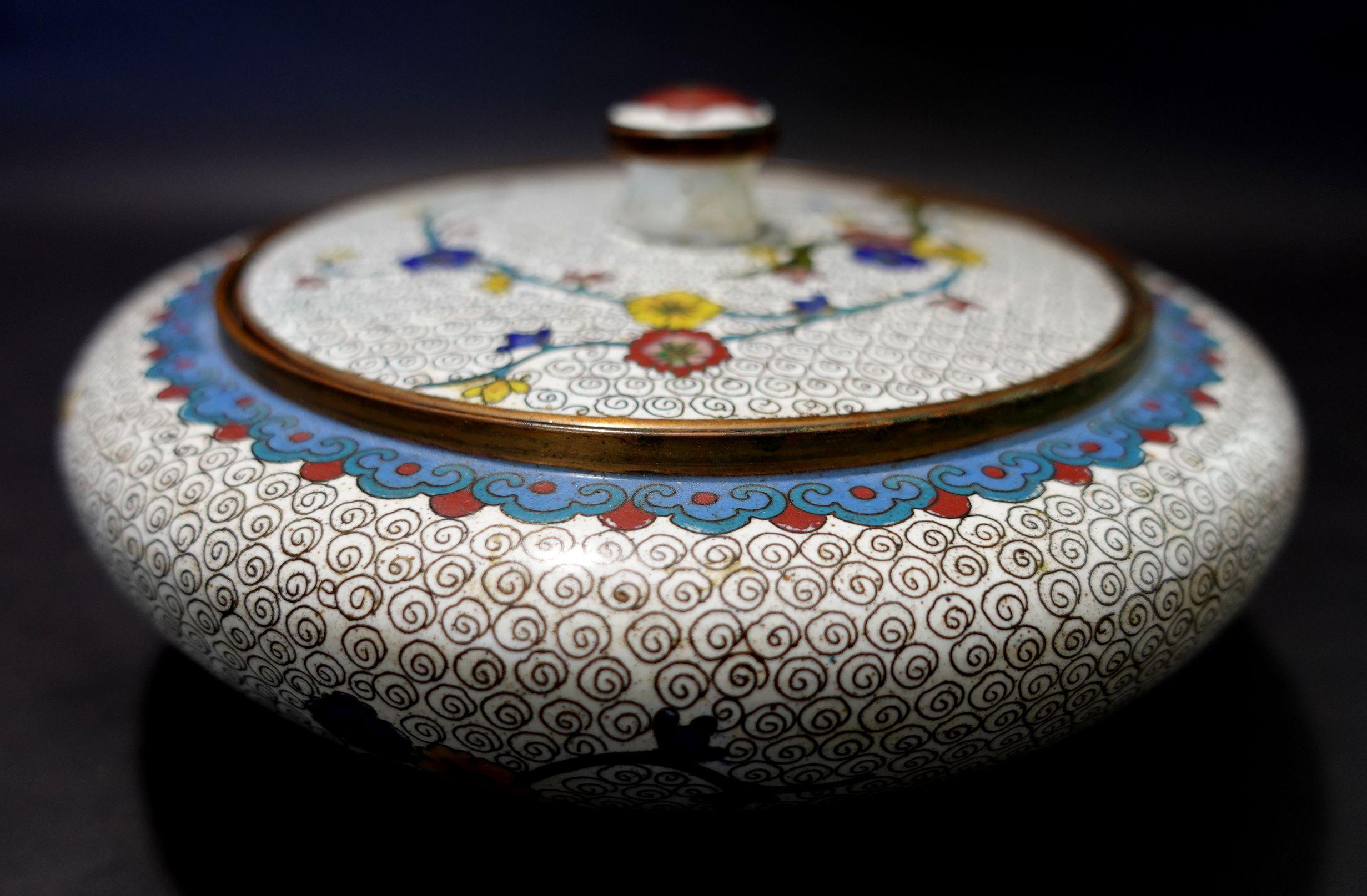 Antique Chinese cloisonné enamel round box with lid depicting floral patterns. A white base tone and colorful floral all around, from the 19th century.
