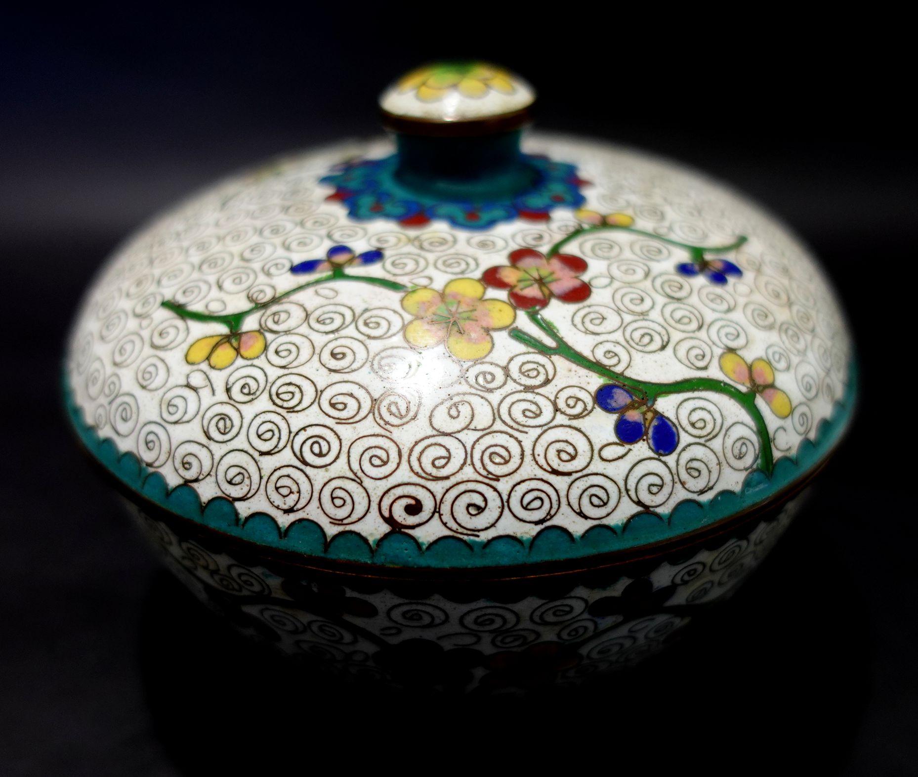Antique Chinese cloisonné enamel round box with lid depicting floral patterns. A white base tone and colorful floral all around, from the 19th century.
