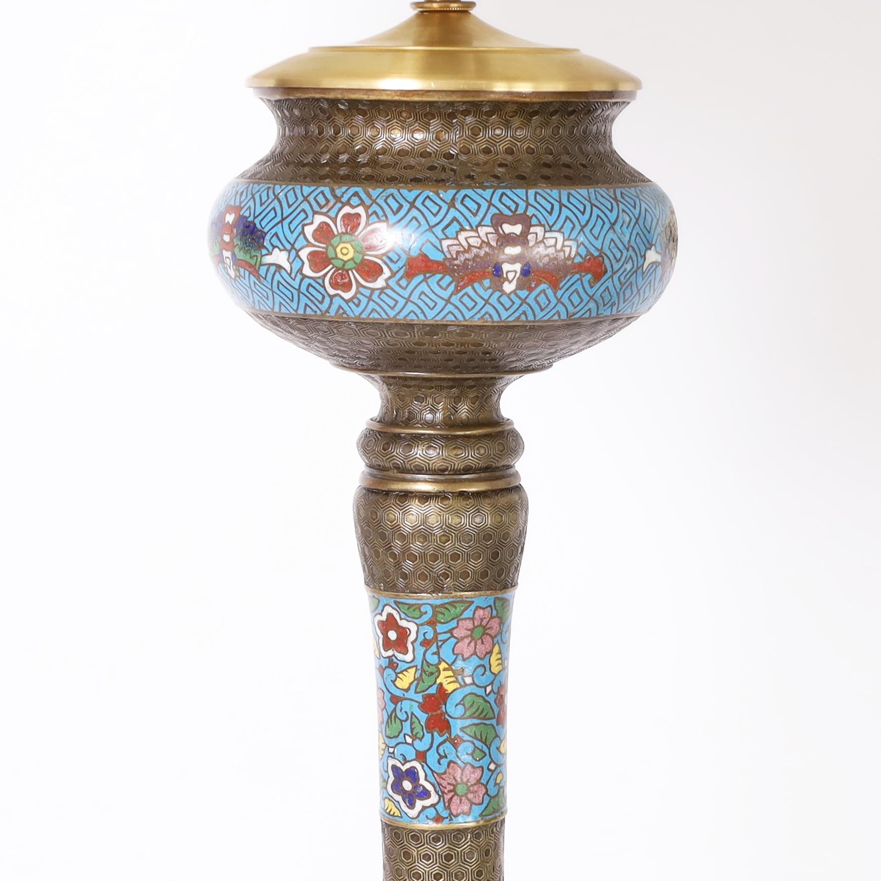 Standout stand up antique Chinese floor lamp crafted in brass with a repeating geometric design and decorated with enamel in a cloisonne technique in colorful floral motifs.