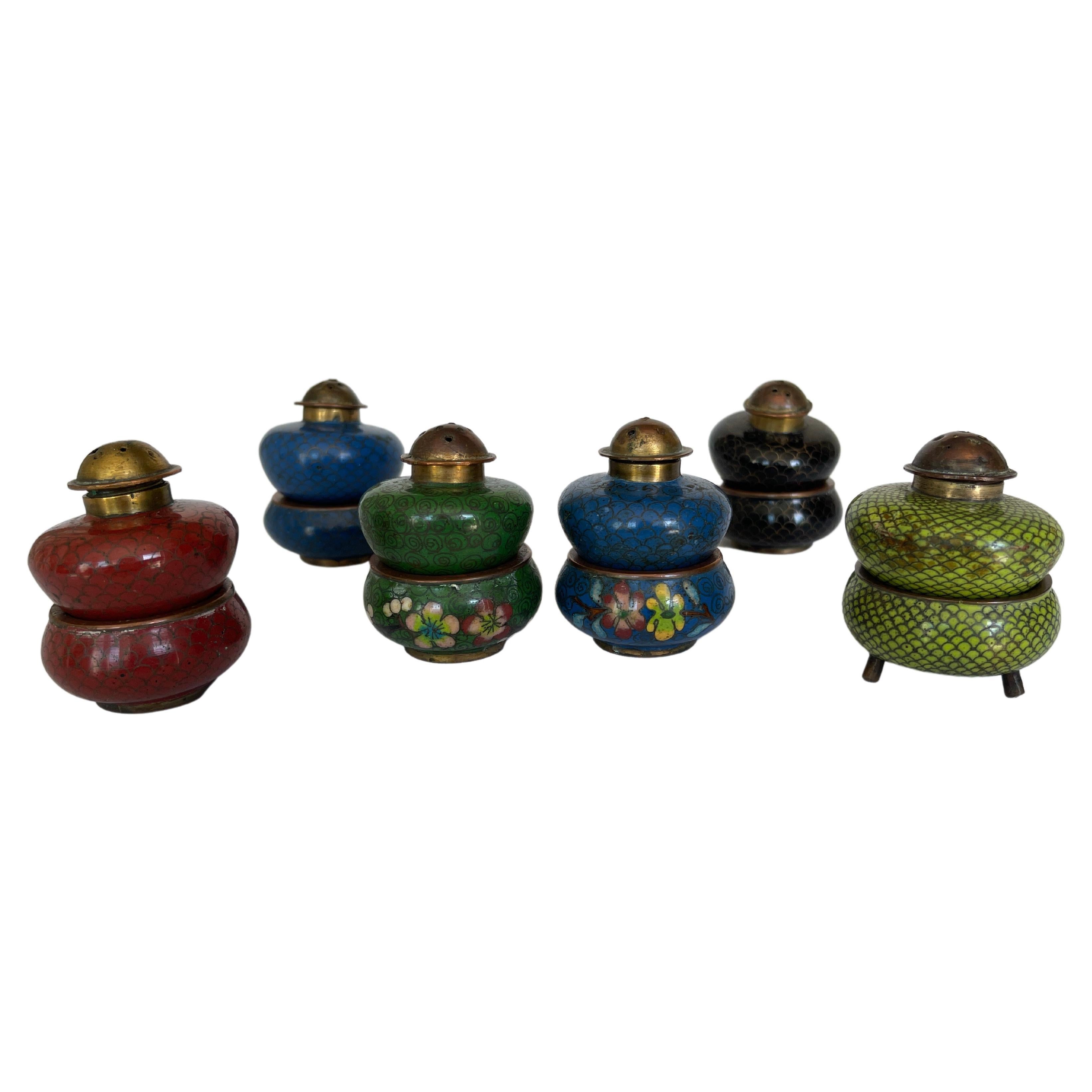 Antique Chinese enamel on copper cloisonné salts and pepper shaker sets.
There are 12 pieces in total. 6 salt cellars, and 6 matching pepper shakers.
Colors include blue, dark green, red, black , and light green. 
The light green salt has brass