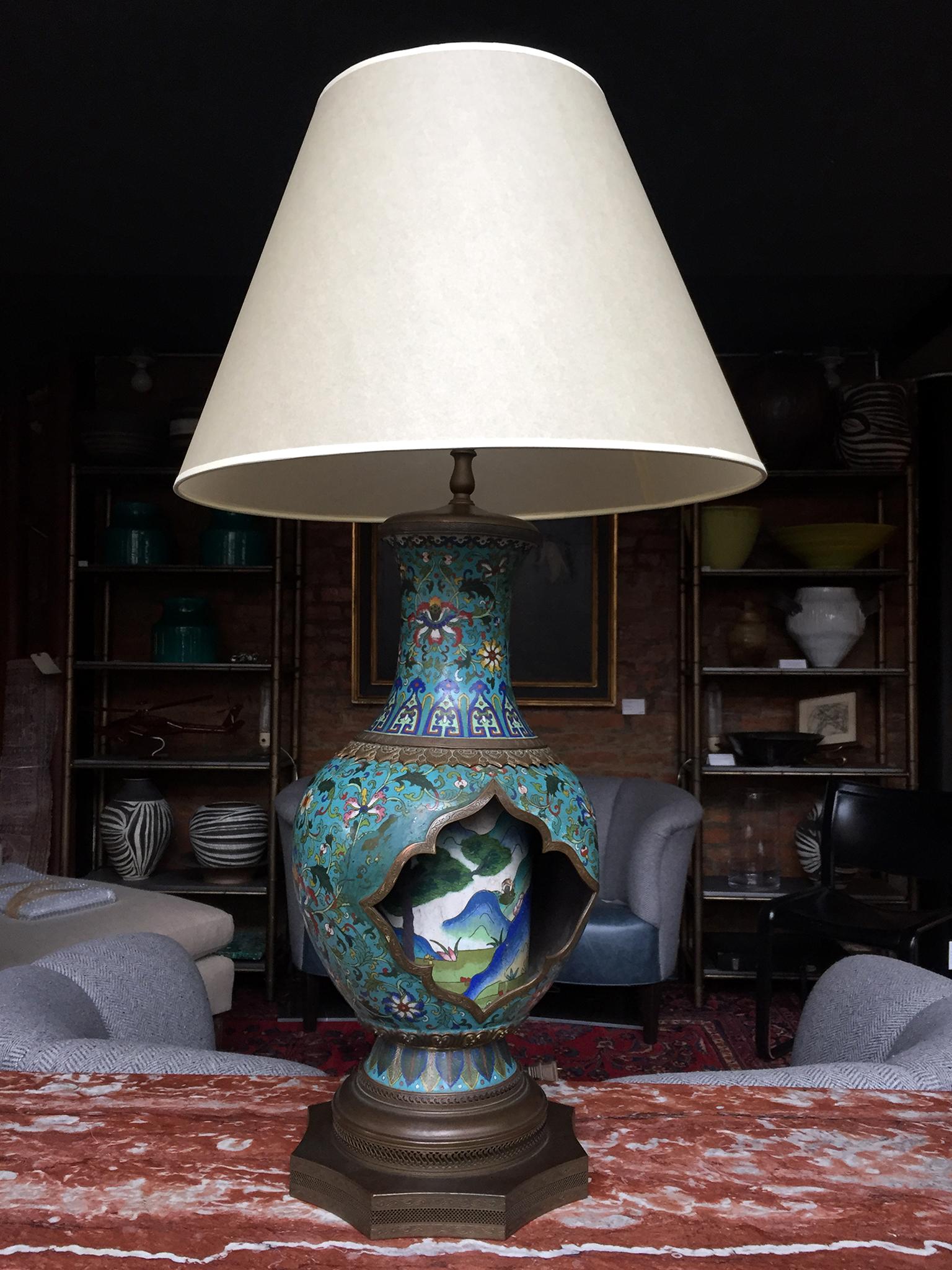 This antique Chinese lamp dates to the late 19th-early 20th century. It is exceptional for its bold color and rich floral pattern. The lamp's body is comprised of a brass vase, which is expertly decorated in the cloisonné technique. Stylized