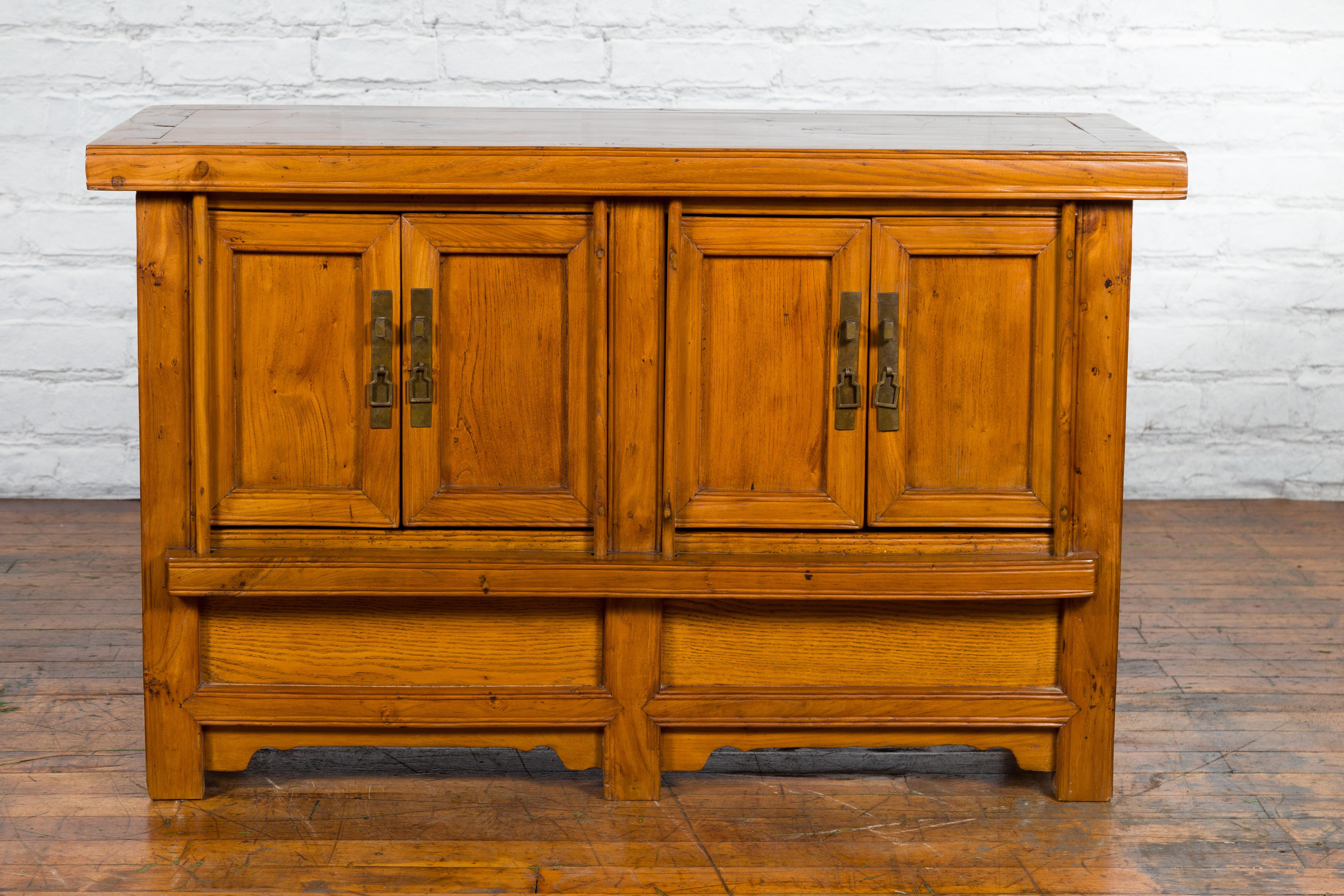 An antique Chinese wooden console cabinet from the early 20th century, with four doors, inner shelves, removable compartments and carved aprons. Created in China during the early years of the 20th century, this console cabinet features a rectangular