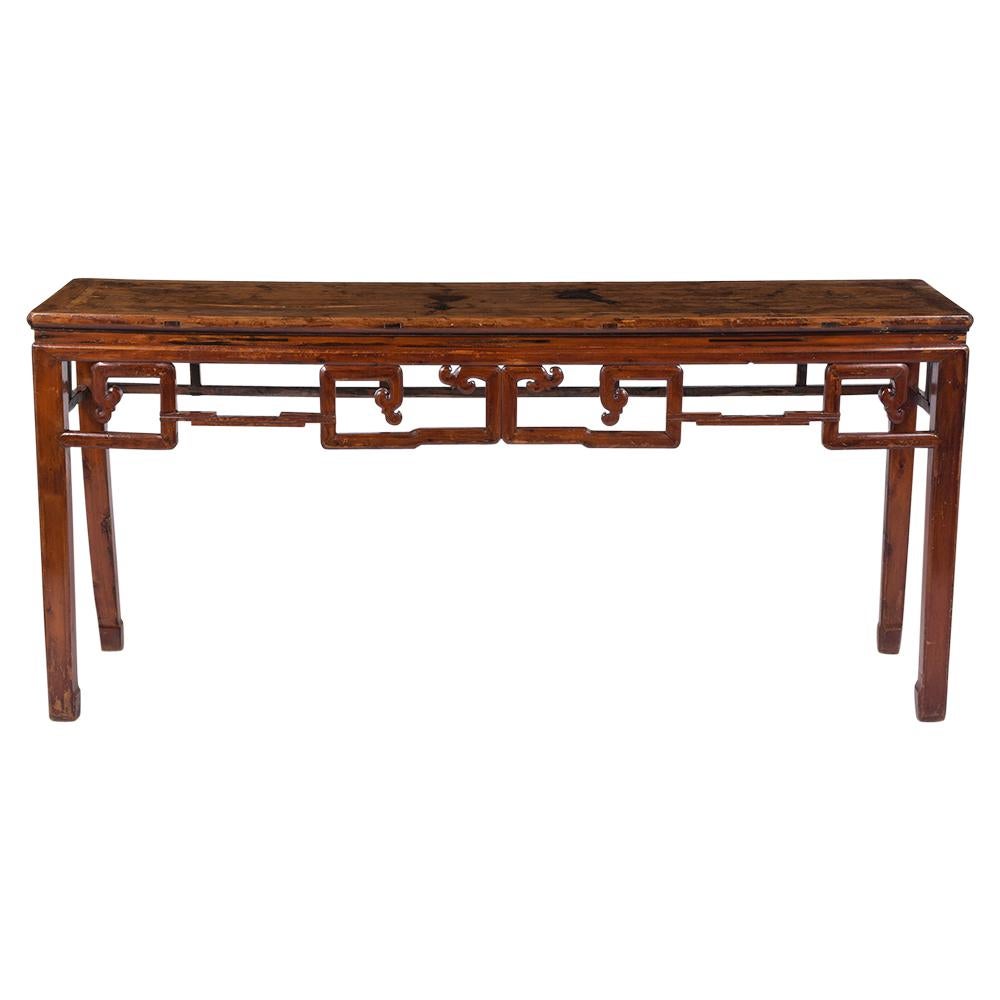 This antique Chinese console made out of elmwood is in good condition and has a uniquely carved and crafted top with molding details. The console has its original red painted color with a unique aged and distressed finish. This antique console is