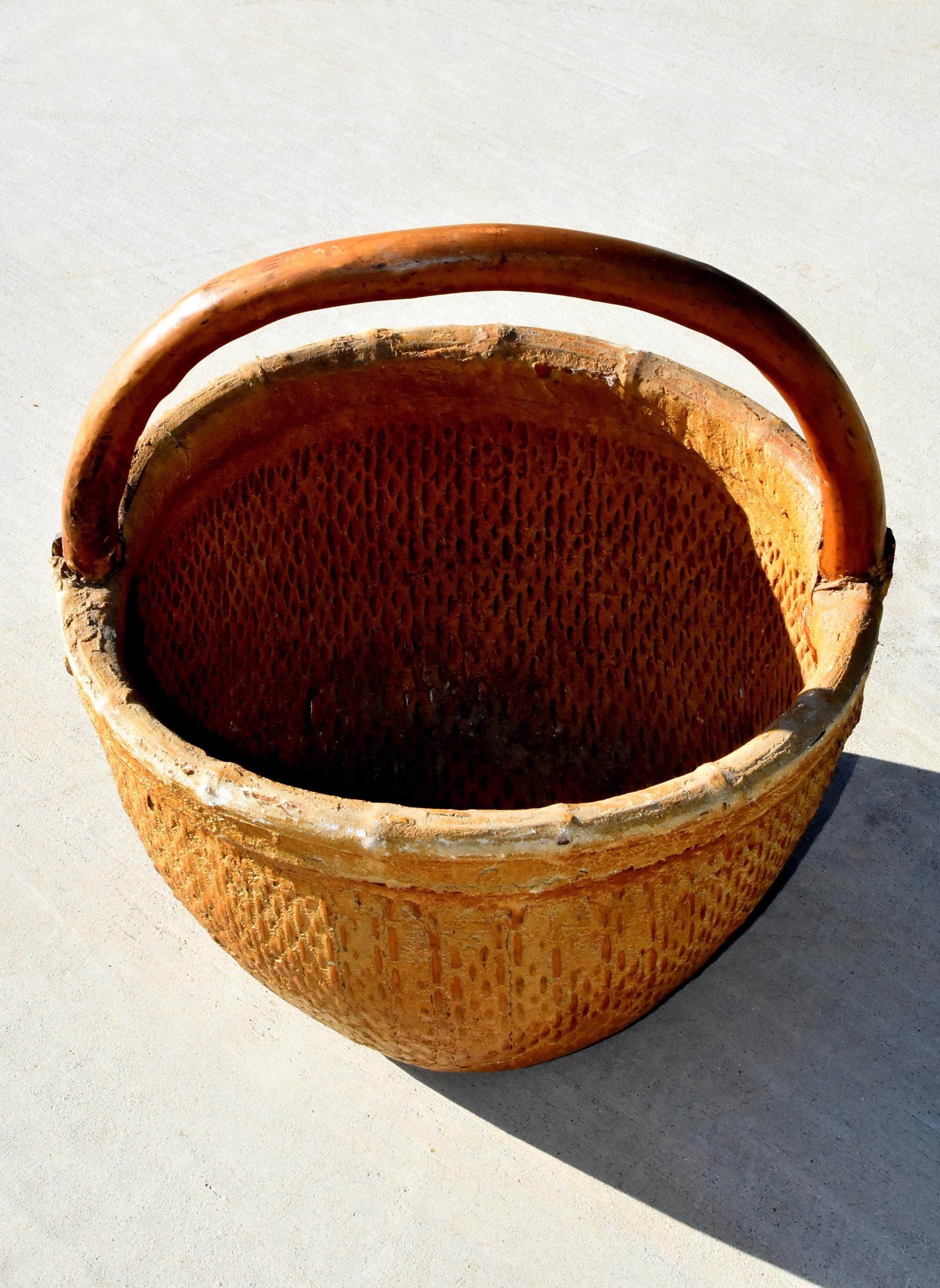 Ein wunderschöner antiker Korb mit einem Henkel aus Baumzweigen und einer eisernen Halterung. Der Weidenkorb ist dicht geflochten und mit Ton und Stoff versiegelt. Dies ist ein großer Korb, der für viele Zwecke verwendet werden kann. Großer