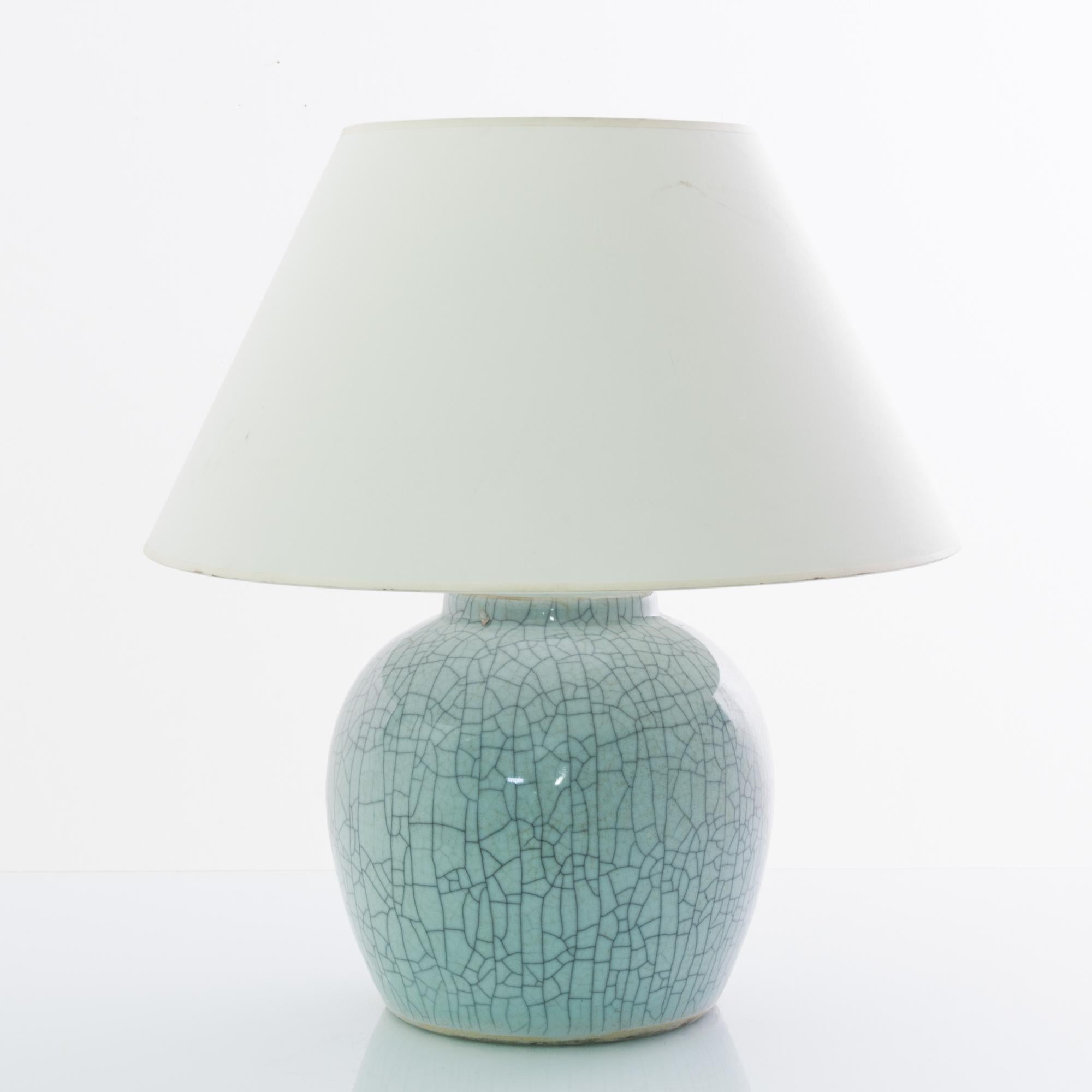 A vintage Chinese vase, fitted with an adjustable brass fixture and E26 lighting socket. The lustrous celadon green glaze is laced with a graphic crackle pattern creating a vivid visual impact. Textured glazes, attractive colors and organic shape
