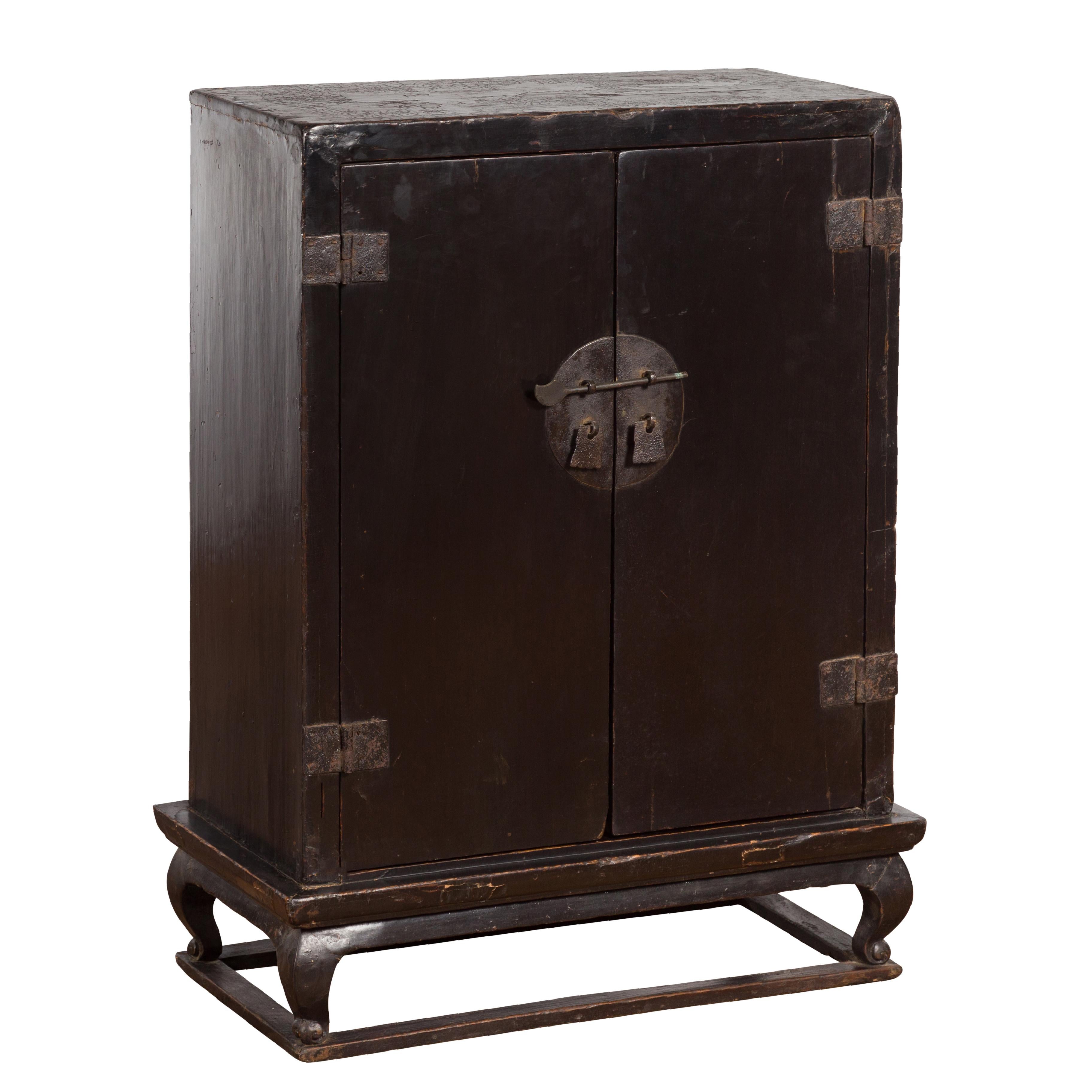 An antique Chinese dark brown lacquer altar shrine from the early 20th century, with carved giltwood motifs. Created in China during the early years of the 20th century, this dark brown lacquer cabinet features a linear silhouette raised on four