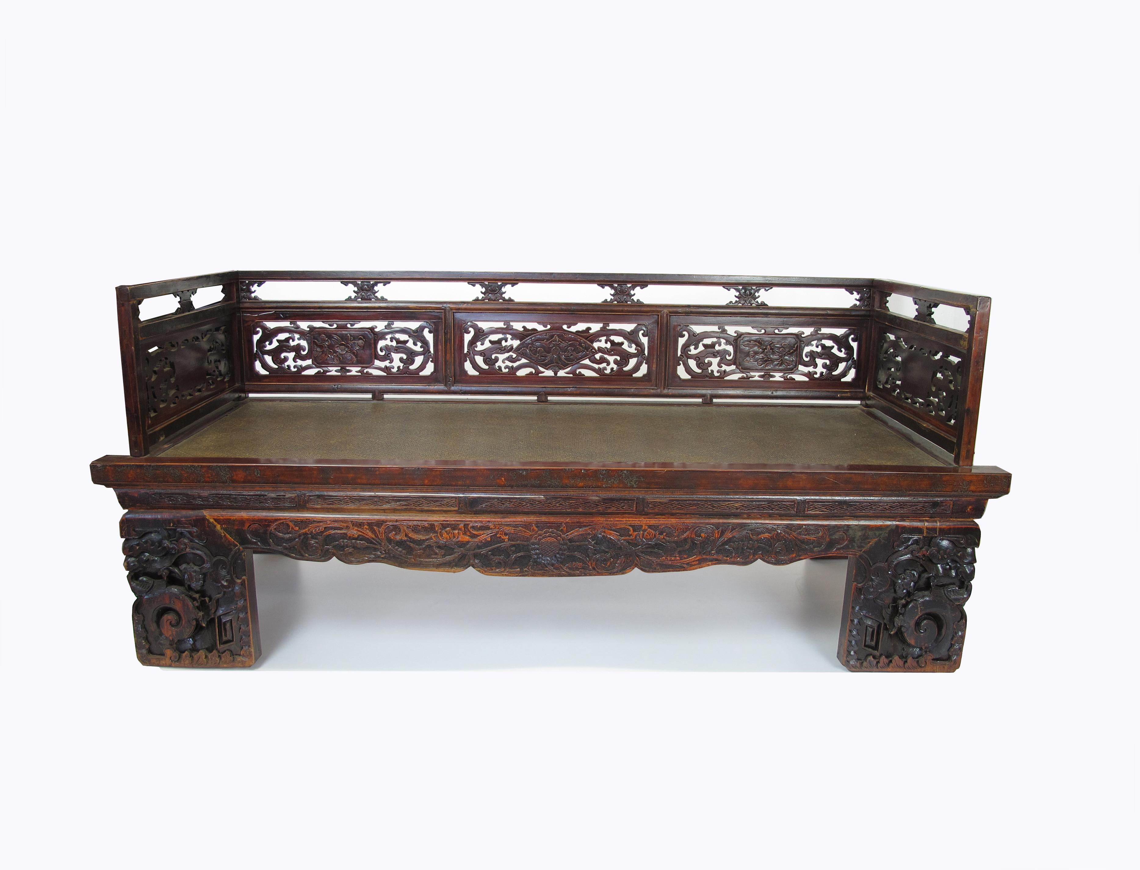 With its beautifully hand carved railing, front apron and legs, this over a century old antique Chinese Luohan bed makes a show piece daybed or love seat in any room. Using traditional tenon and mortise joinery, this solid elm daybed is not just a